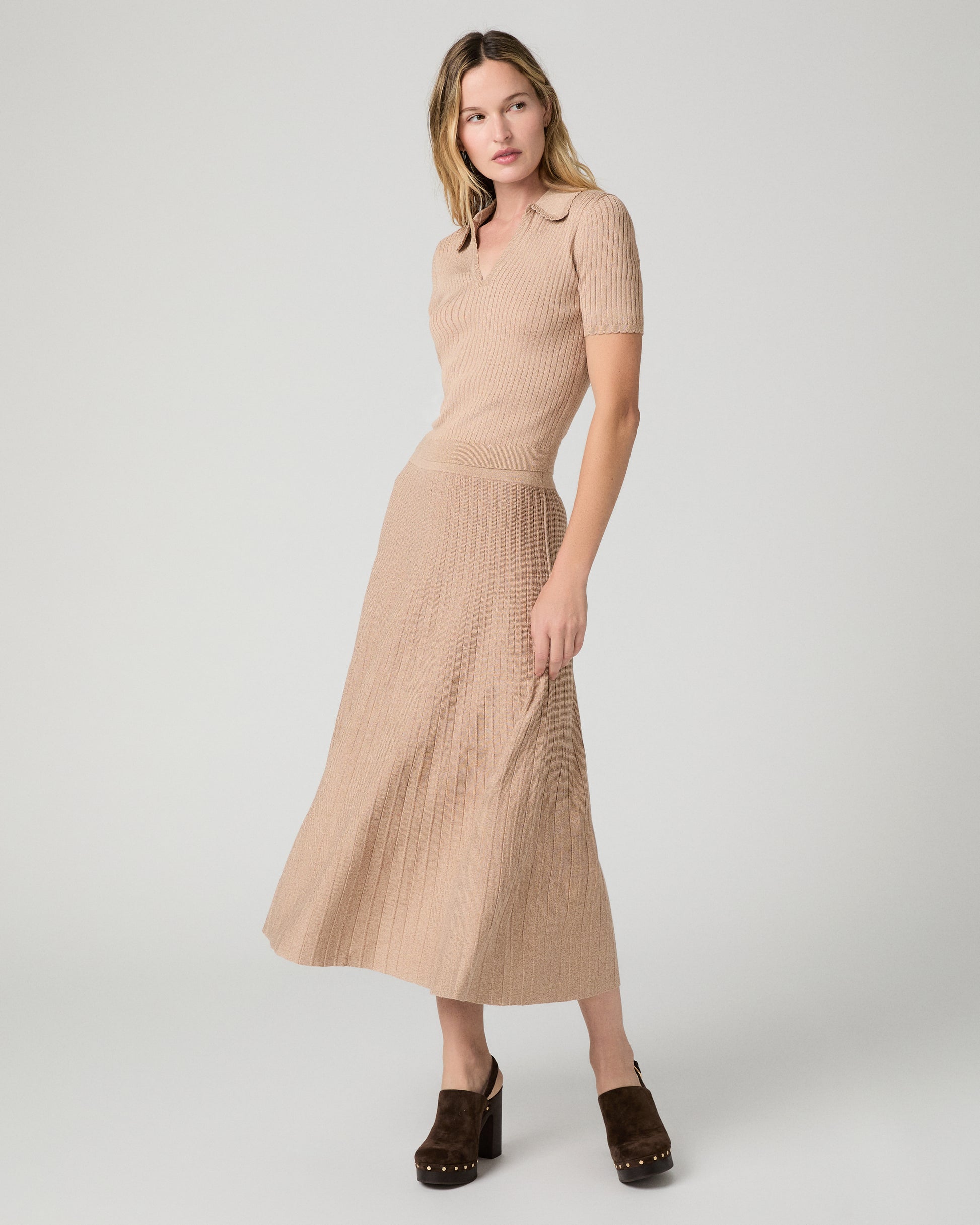 Women wearing a tan top and matching skirt paired with brown heels against a white background
