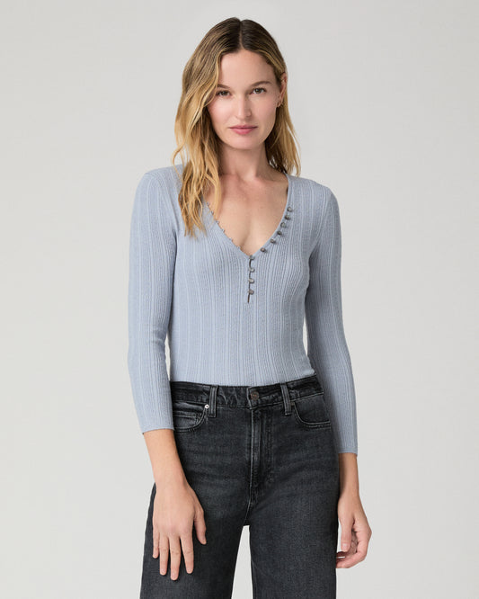 Women wearing a light blue top paired with black jeans against a white background