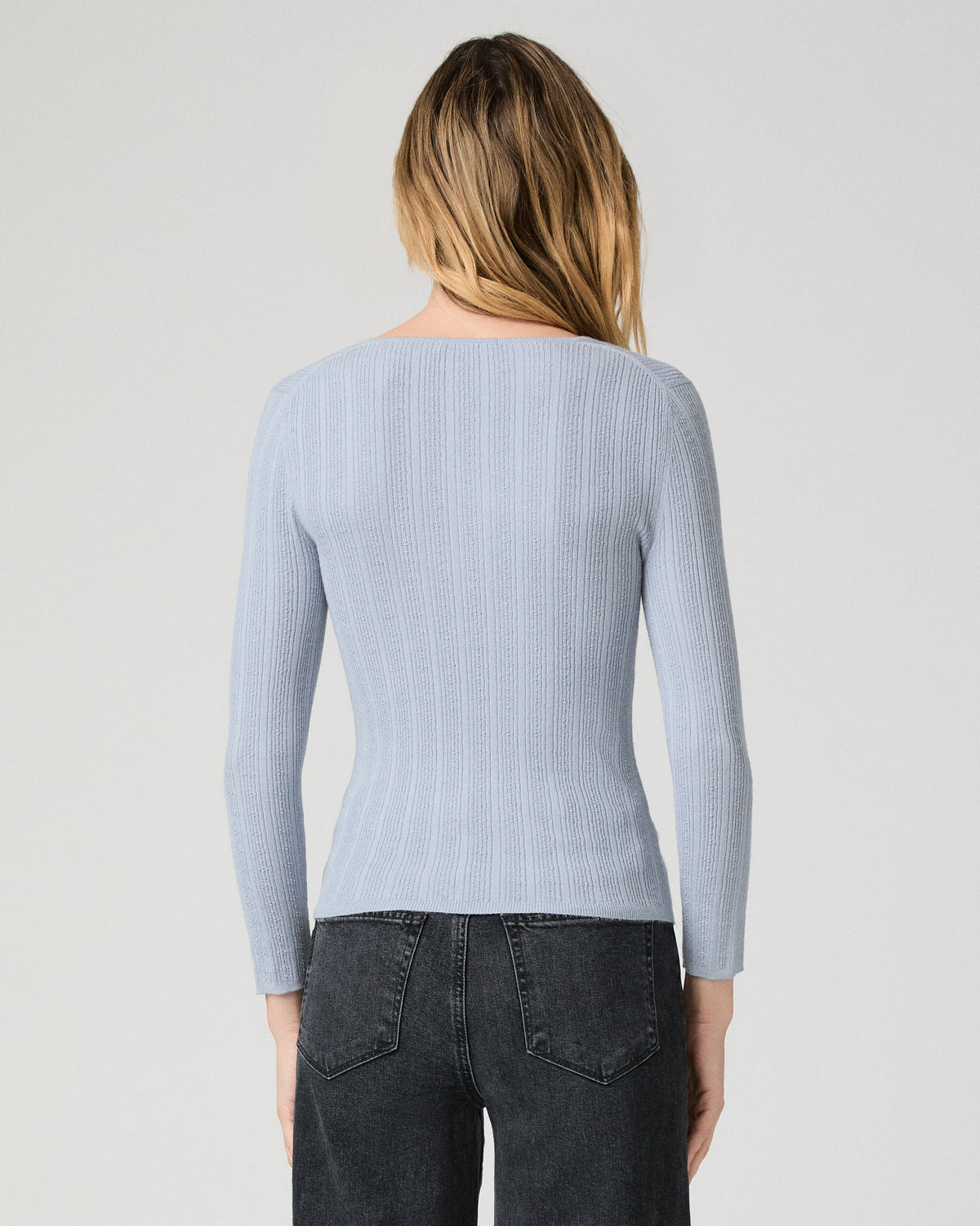 Women wearing a light blue top paired with black jeans against a white background