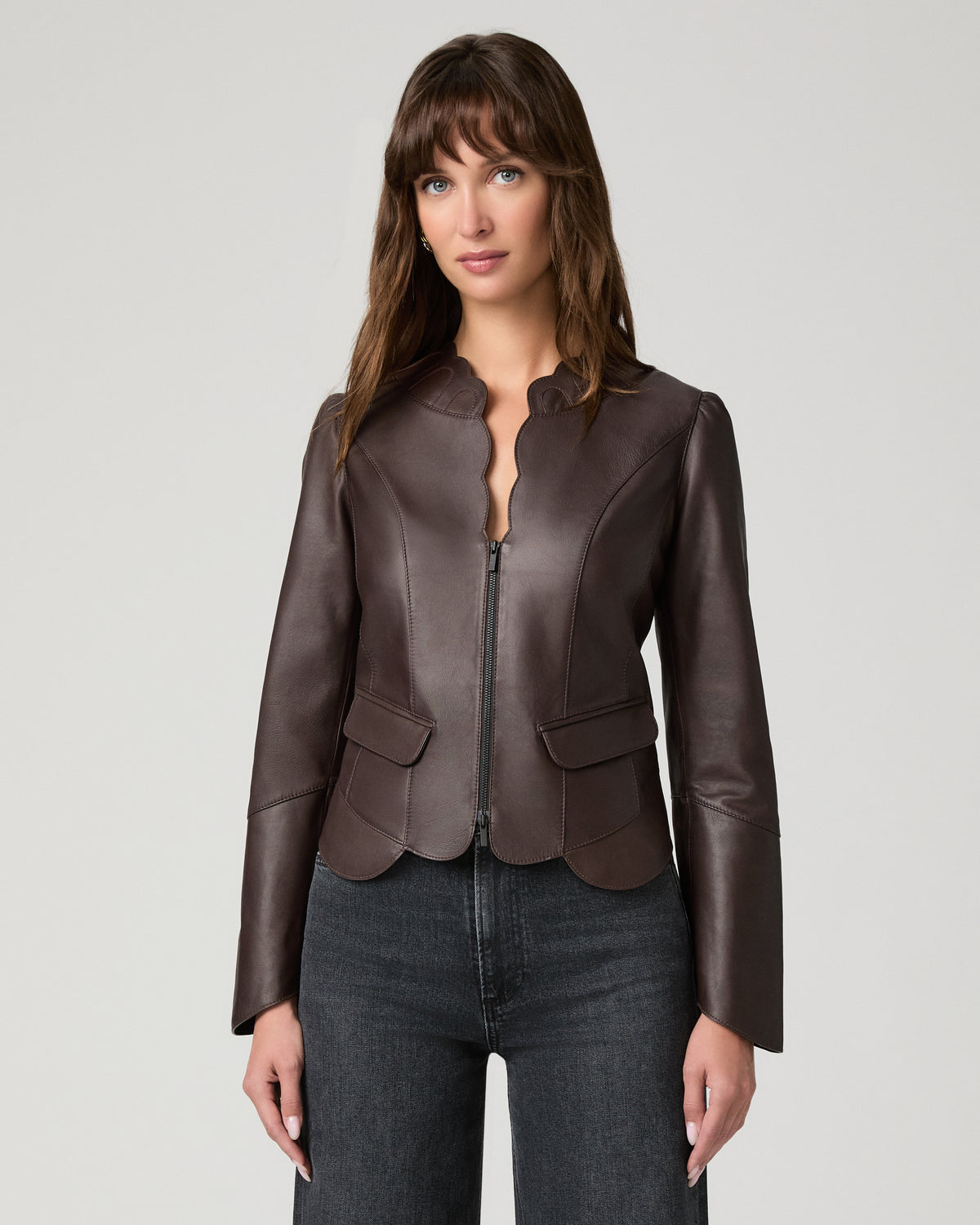 Women wearing a burgundy leather jacket paired with black jeans against a white background
