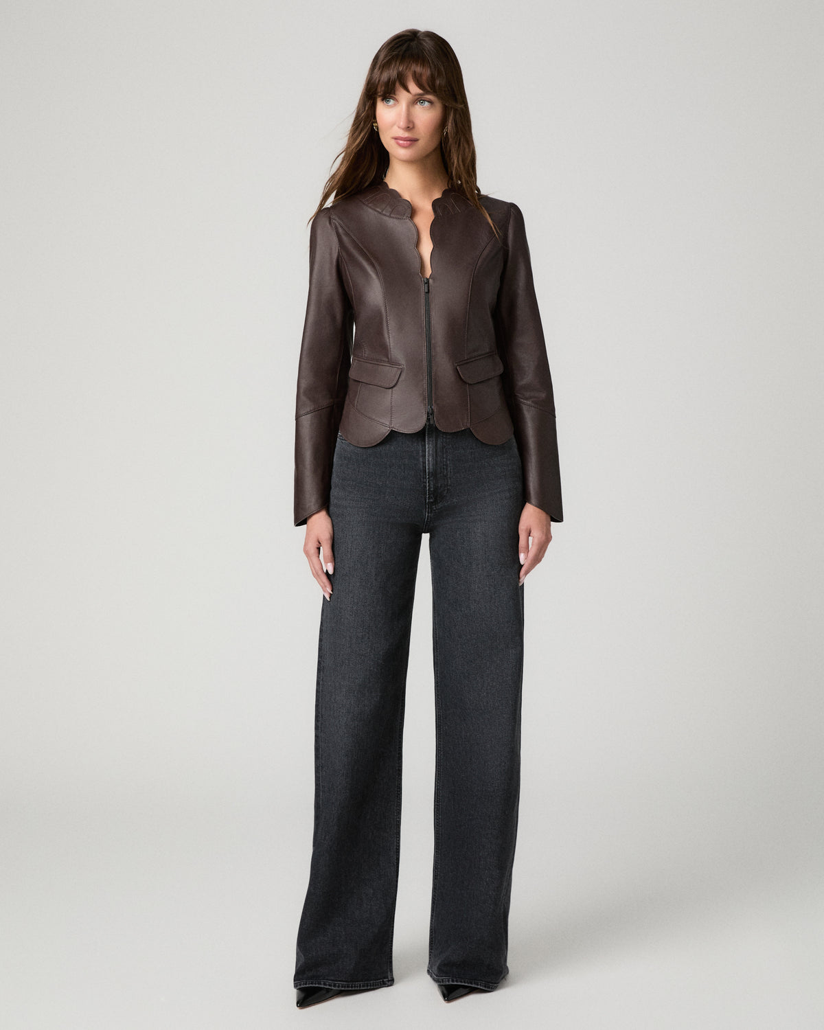 Women wearing a burgundy leather jacket paired with black jeans against a white background