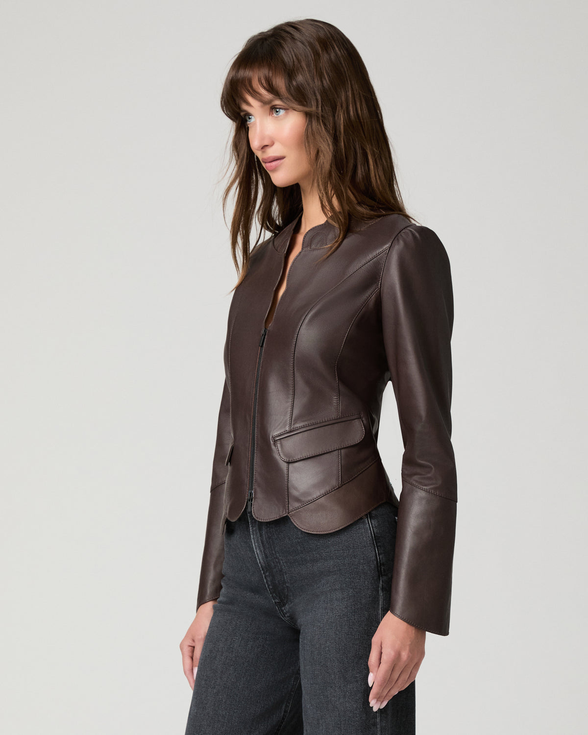 Women wearing a burgundy leather jacket paired with black jeans against a white background