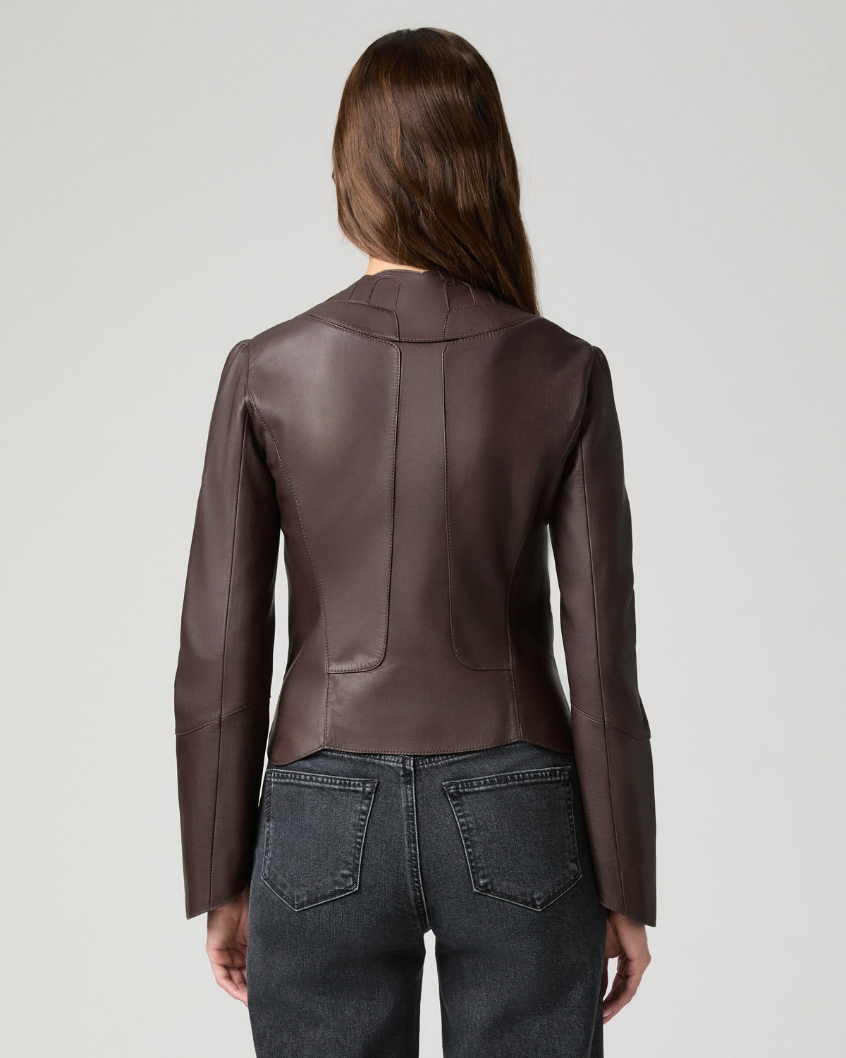 Women wearing a burgundy leather jacket paired with black jeans against a white background