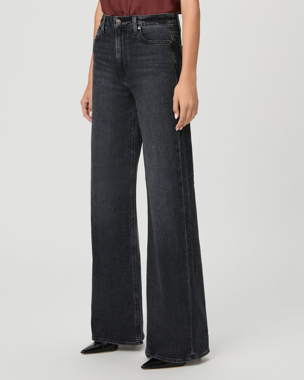 A woman modeling a brown short-sleeve top and black wide-leg pants against a light gray studio background.