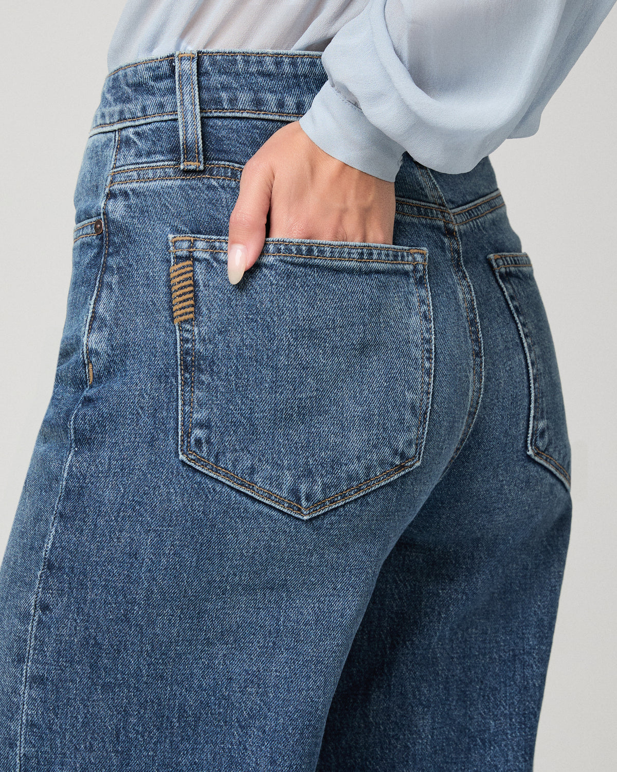 Woman wearing maroon top and black jeans against a white background