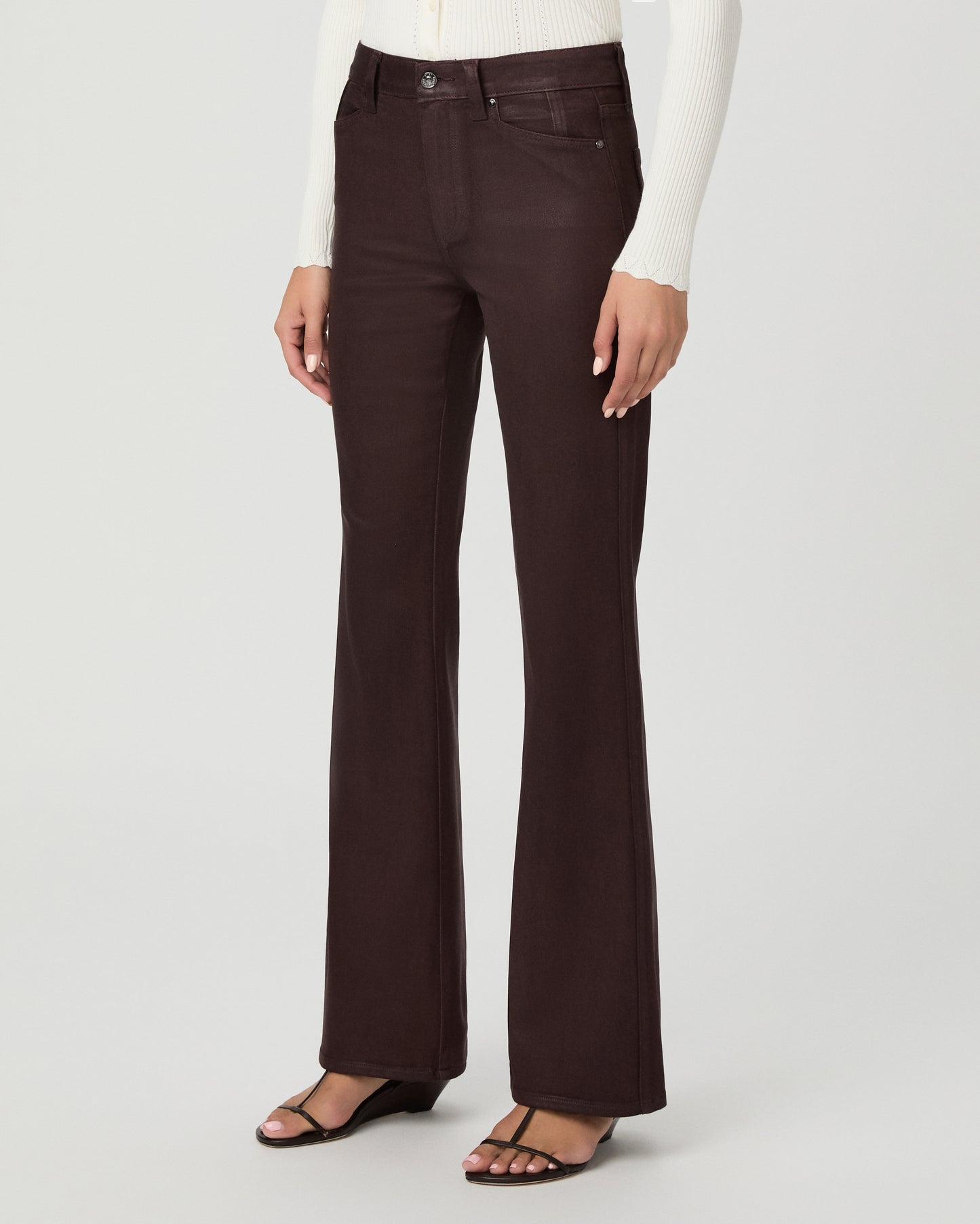 A woman modeling a cream long-sleeve knit cardigan with a V-neck and button front, paired with dark brown wide-leg pants, against a light gray studio background.