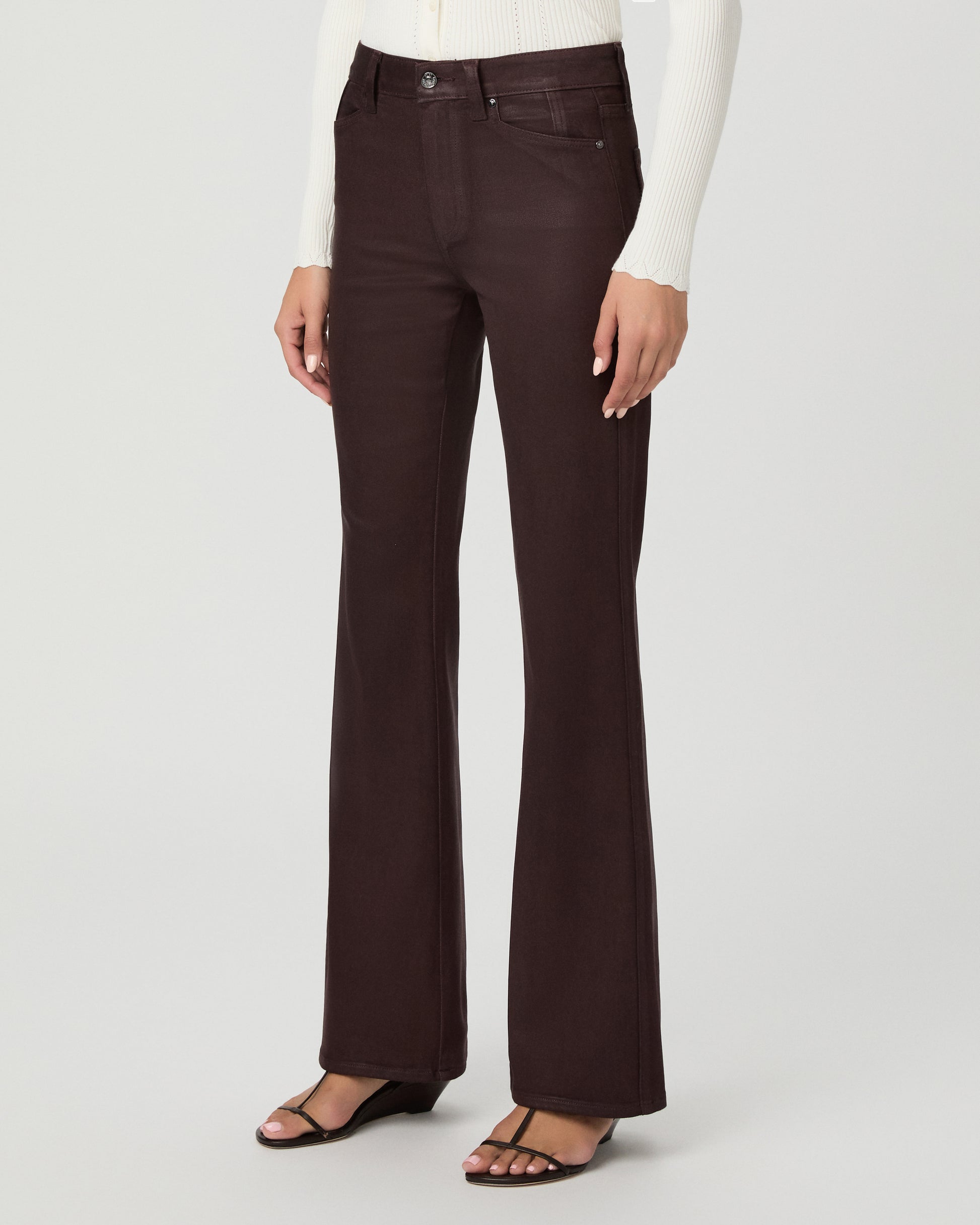 A woman modeling a cream long-sleeve knit cardigan with a V-neck and button front, paired with dark brown wide-leg pants, against a light gray studio background.