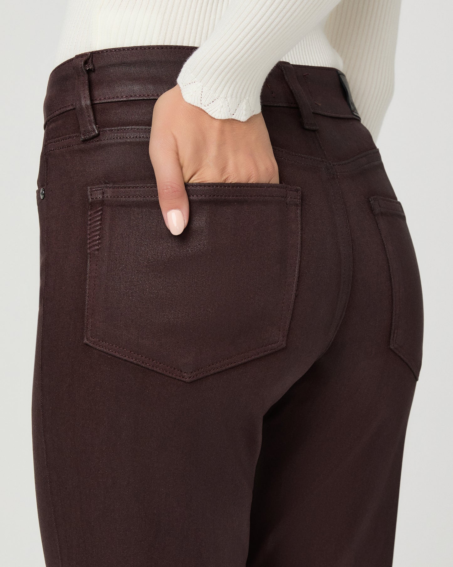 A woman modeling a cream long-sleeve knit cardigan with a V-neck and button front, paired with dark brown wide-leg pants, against a light gray studio background.