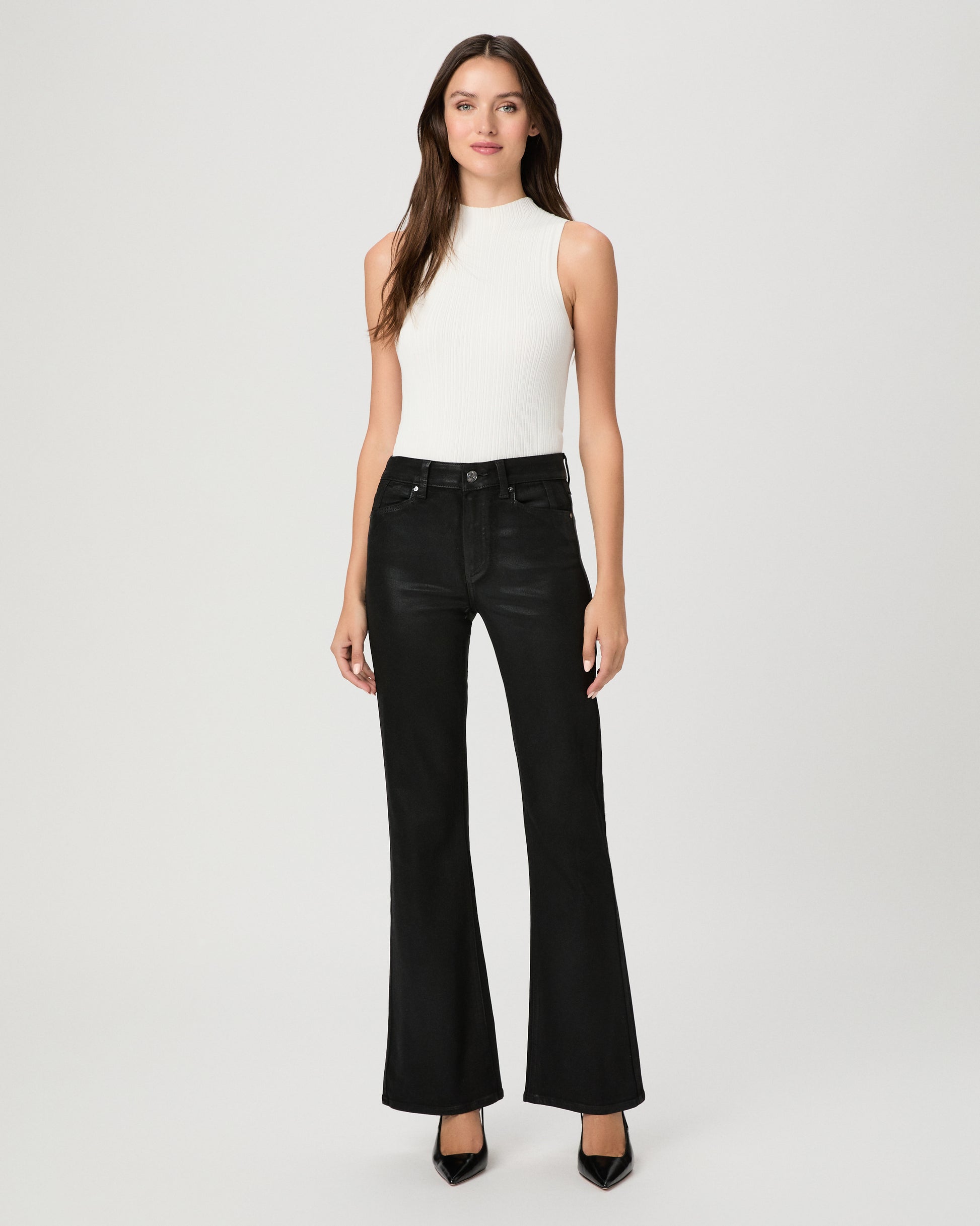 A woman modeling a sleeveless white mock-neck top and black wide-leg flare jeans against a light gray studio background.