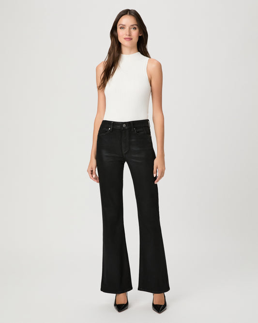 A woman modeling a sleeveless white mock-neck top and black wide-leg flare jeans against a light gray studio background.