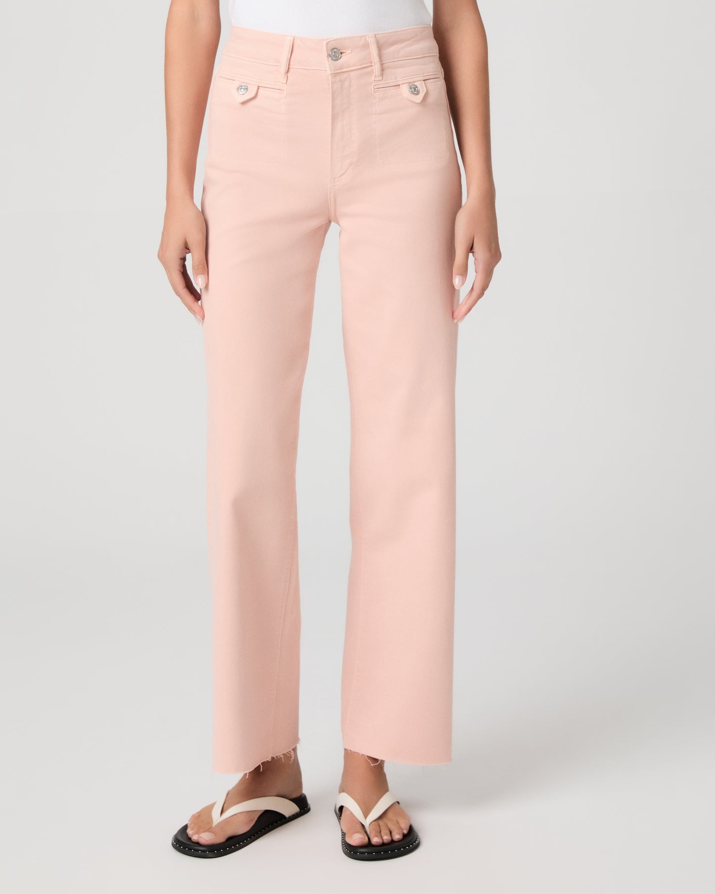 Woman wearing a white tank top and pink pants on a white background