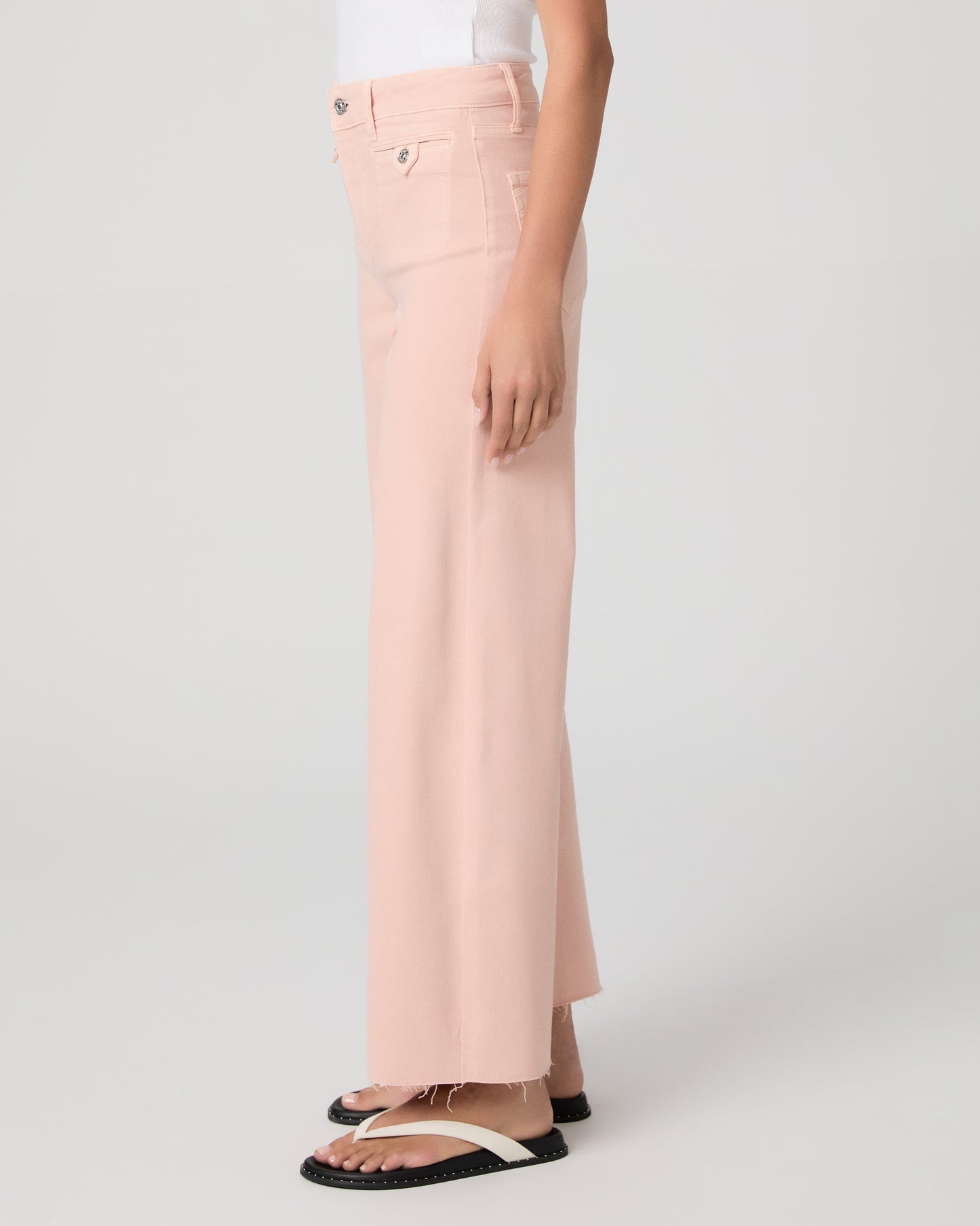 Woman wearing a white tank top and pink pants on a white background