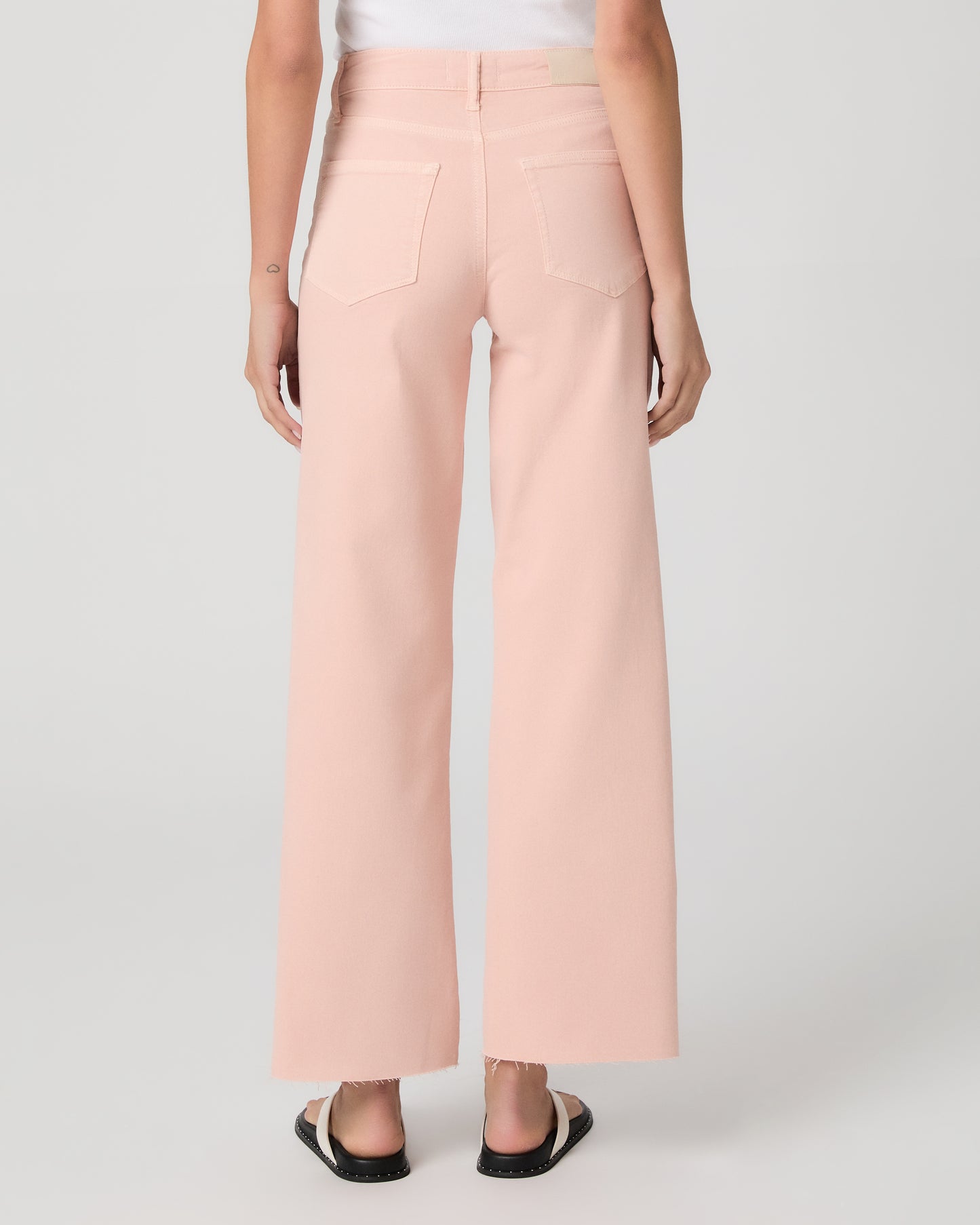 Woman wearing a white tank top and pink pants on a white background