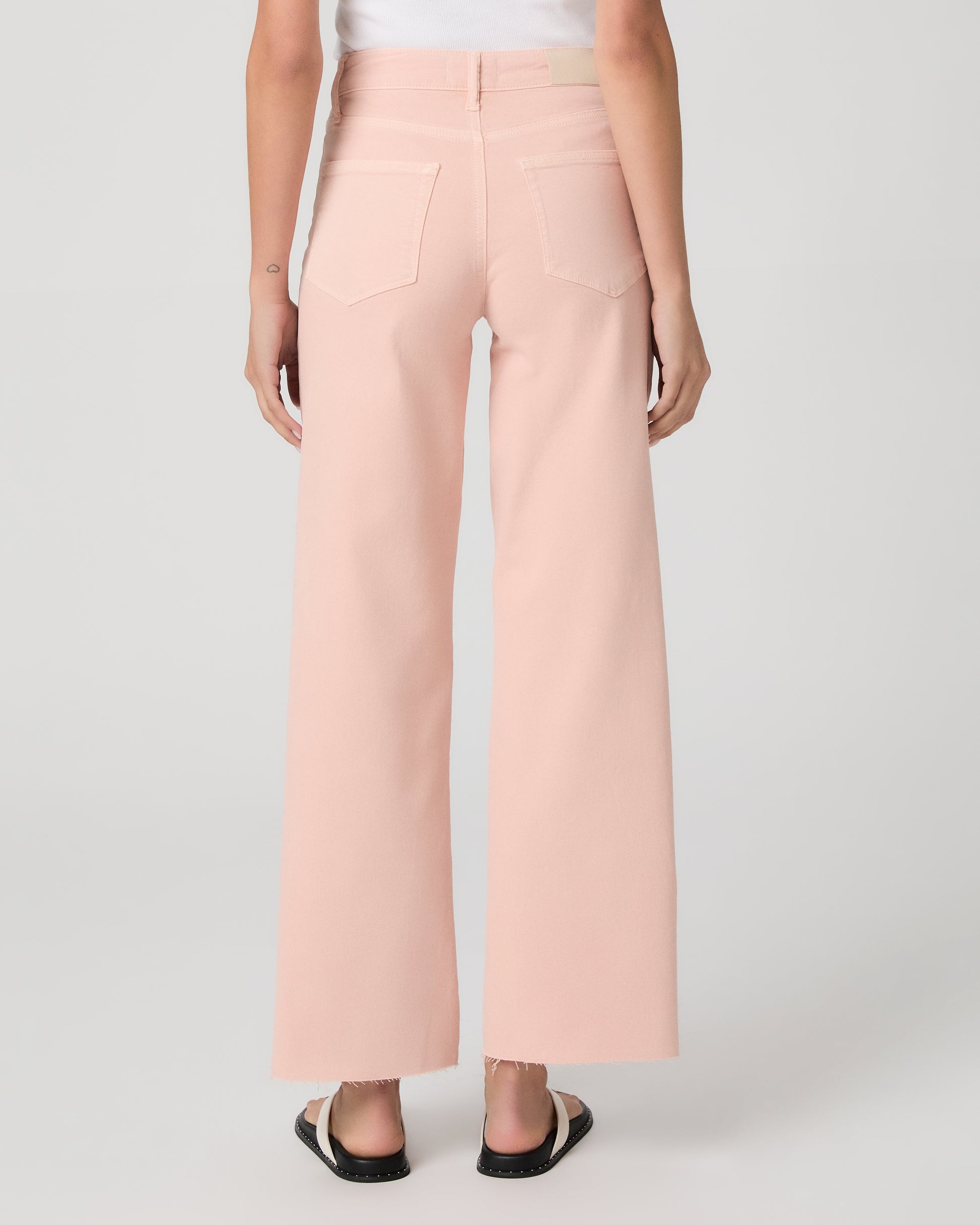 Woman wearing a white tank top and pink pants on a white background