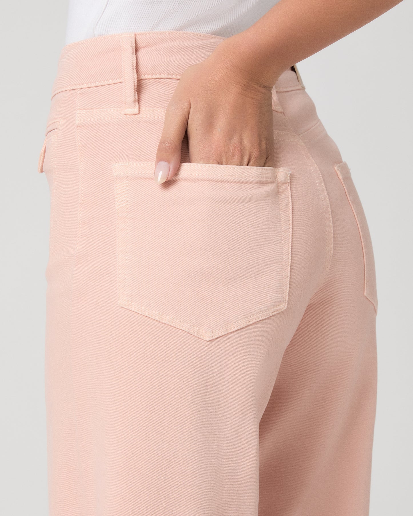 Woman wearing a white tank top and pink pants on a white background