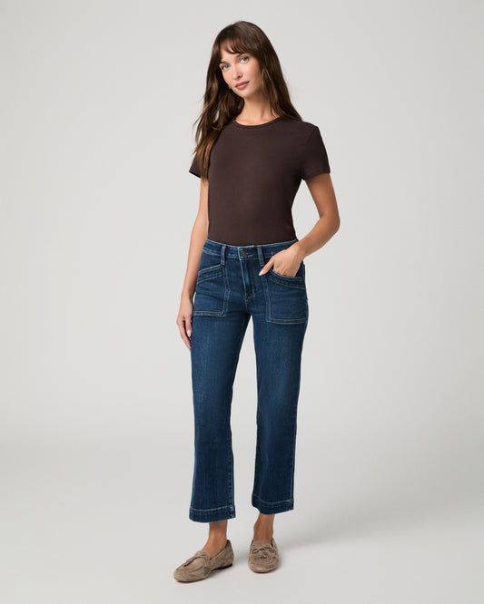 Woman wearing a brown top paired with  dark pants against a white background