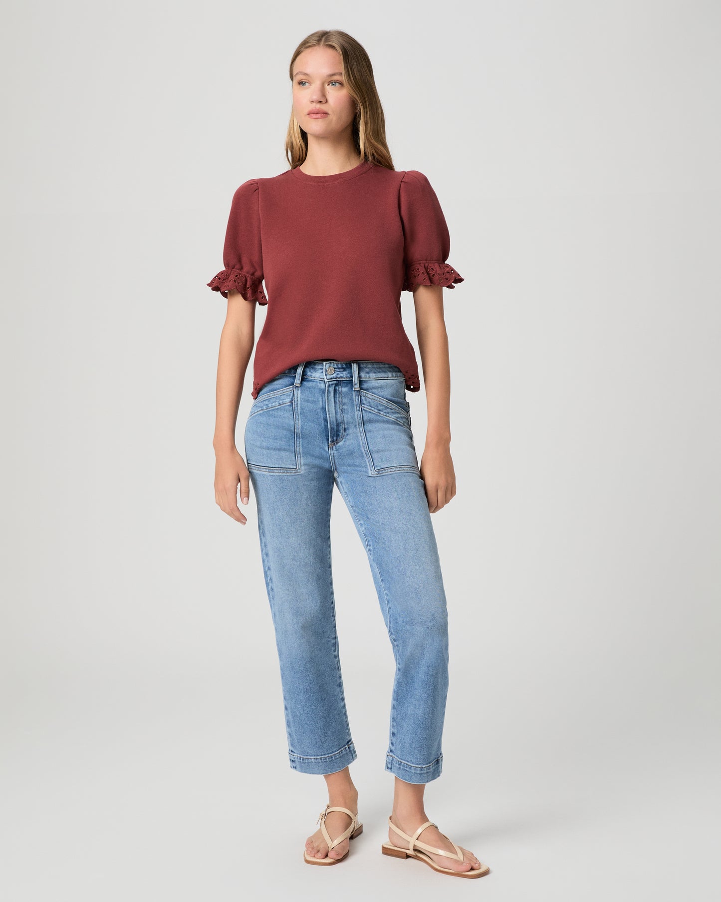 Woman wearing a maroon top and blue jeans on a white background