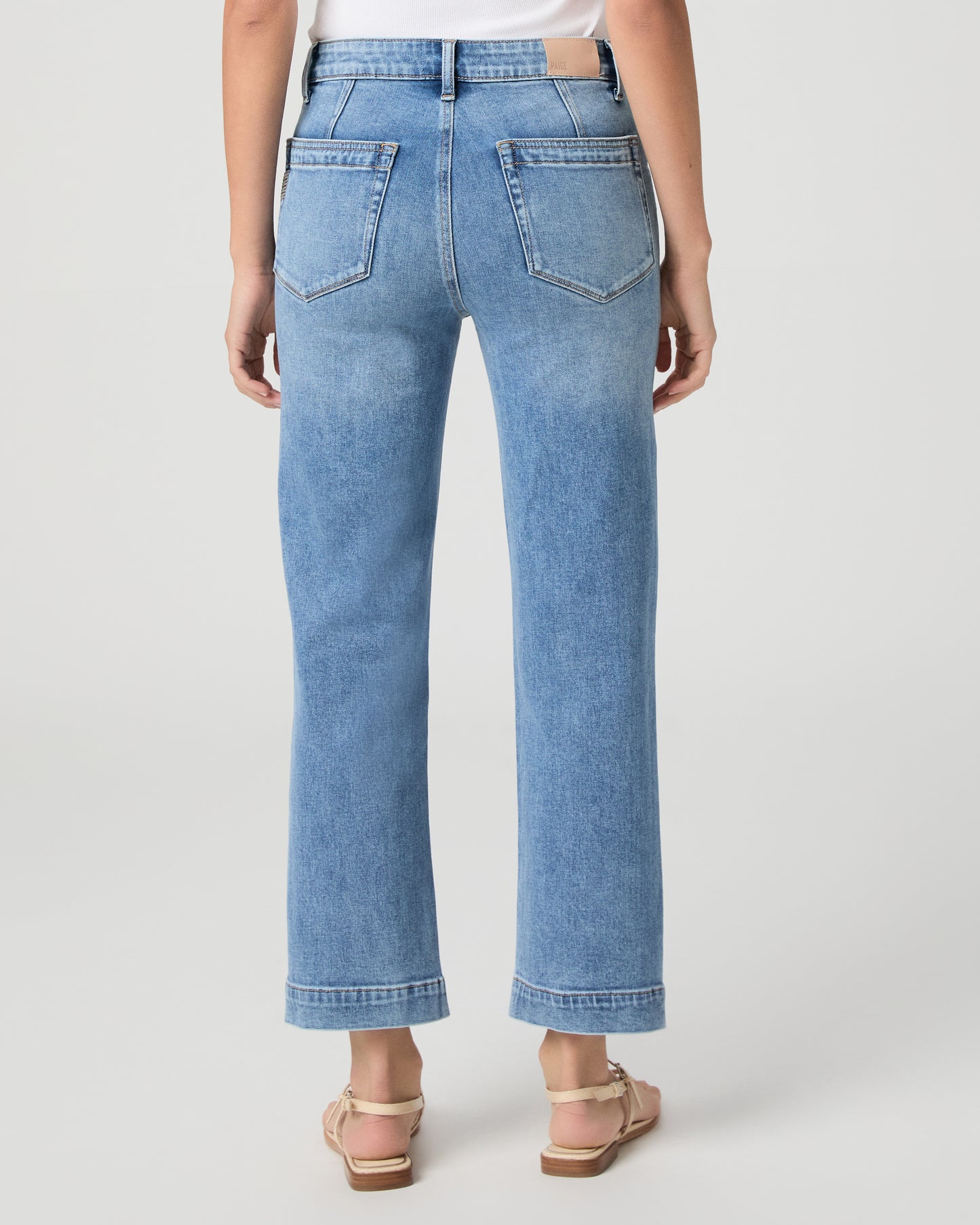 Woman wearing a maroon top and blue jeans on a white background
