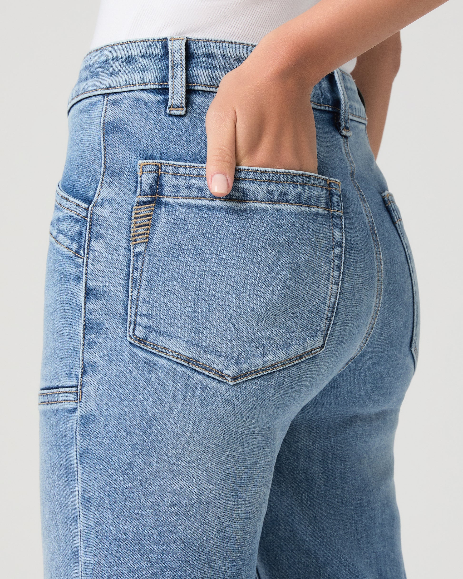 Woman wearing a maroon top and blue jeans on a white background