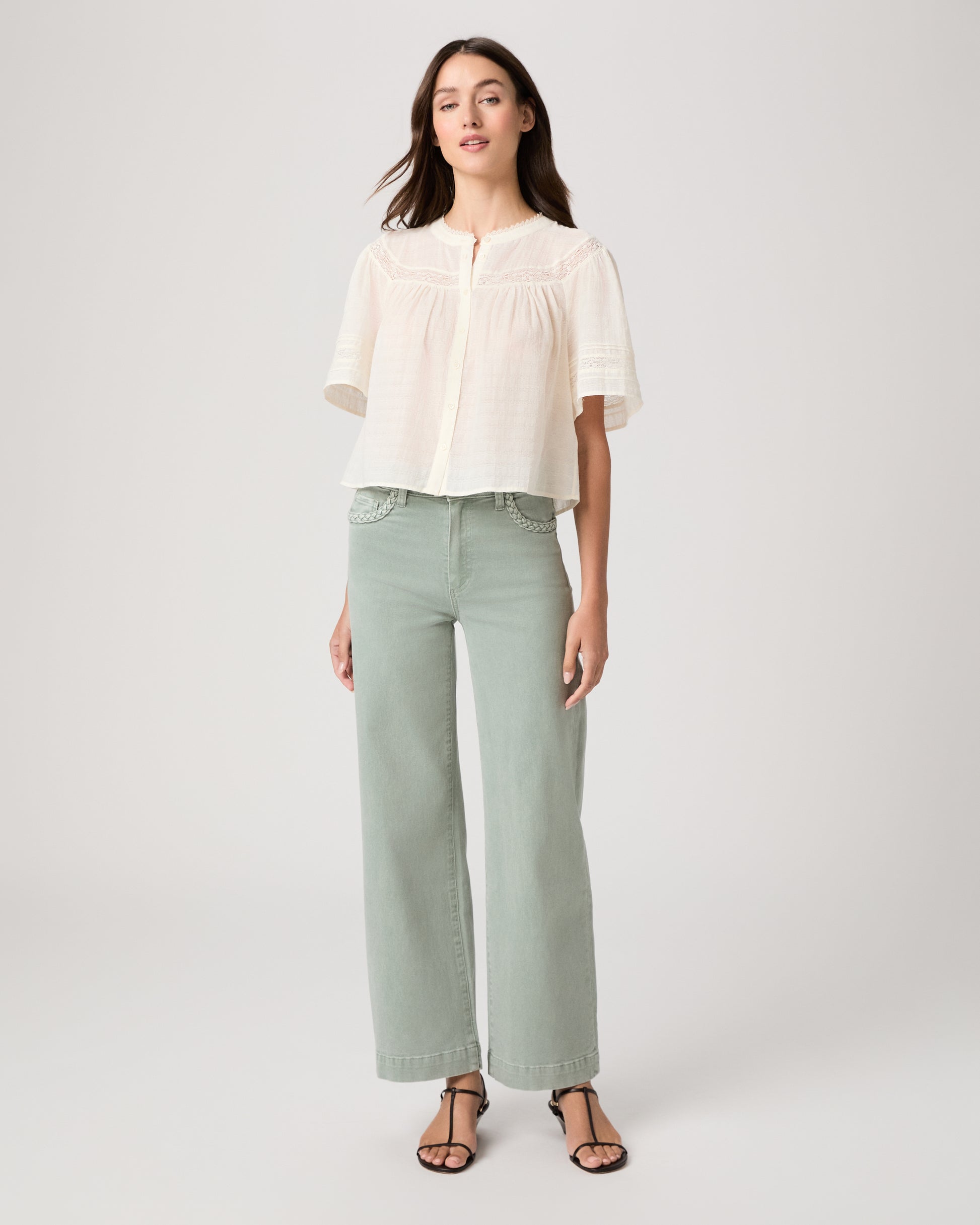 Model wearing a light green pant paired with a white top and brown sandals