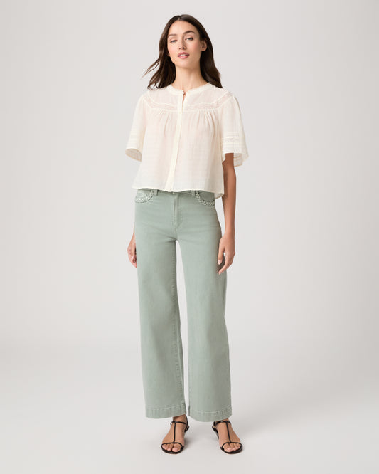 Model wearing a light green pant paired with a white top and brown sandals