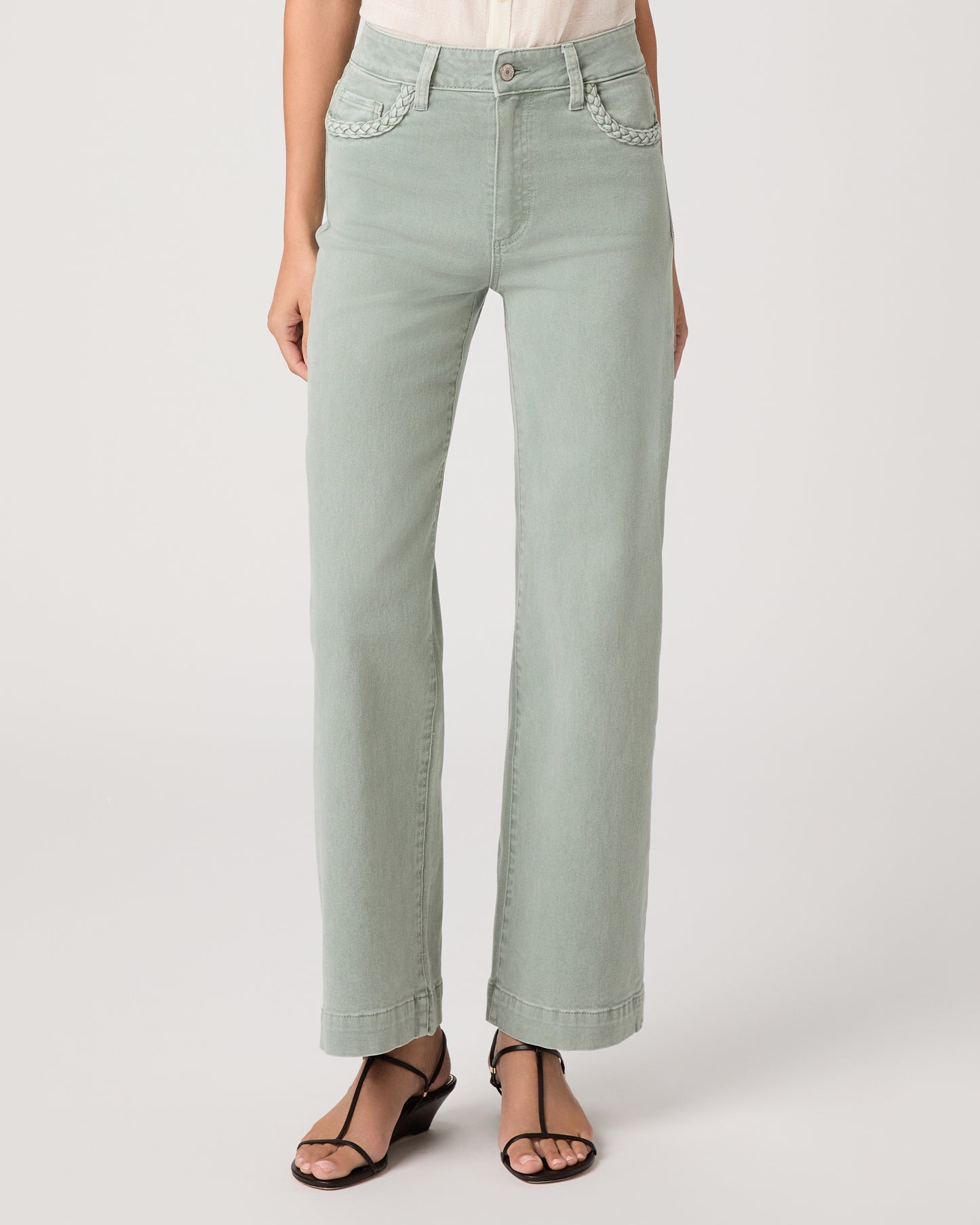 Model wearing a light green pant paired with a white top and brown sandals