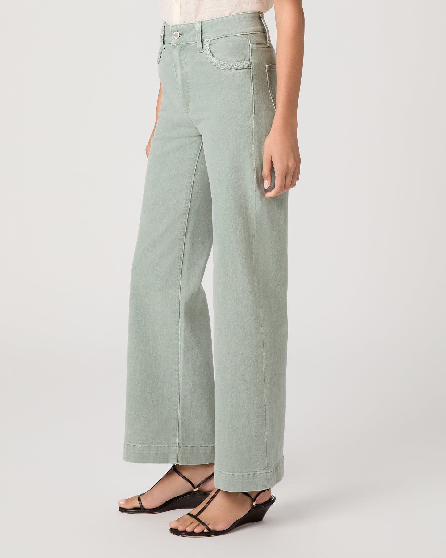 Model wearing a light green pant paired with a white top and brown sandals
