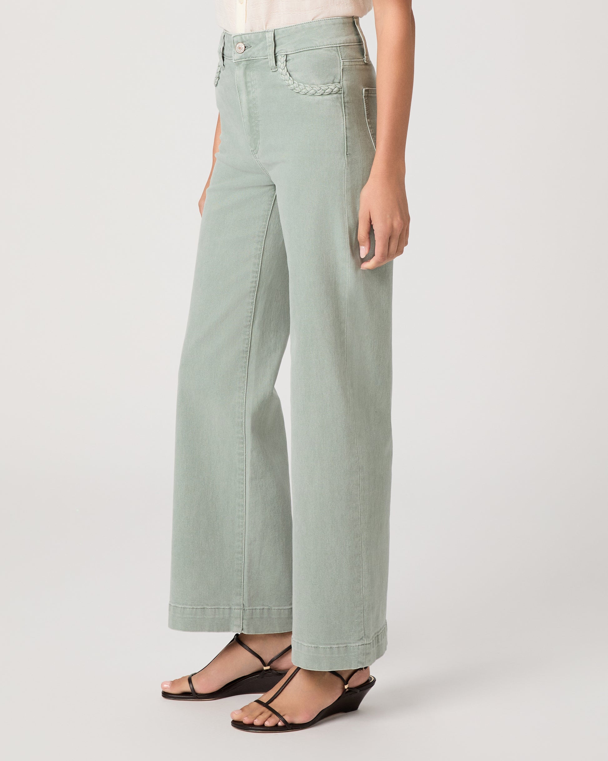 Model wearing a light green pant paired with a white top and brown sandals