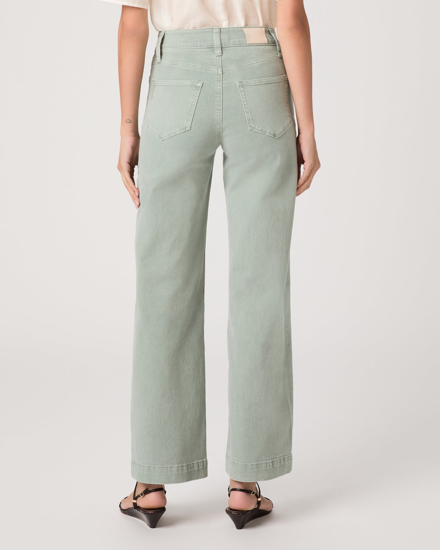 Model wearing a light green pant paired with a white top and brown sandals