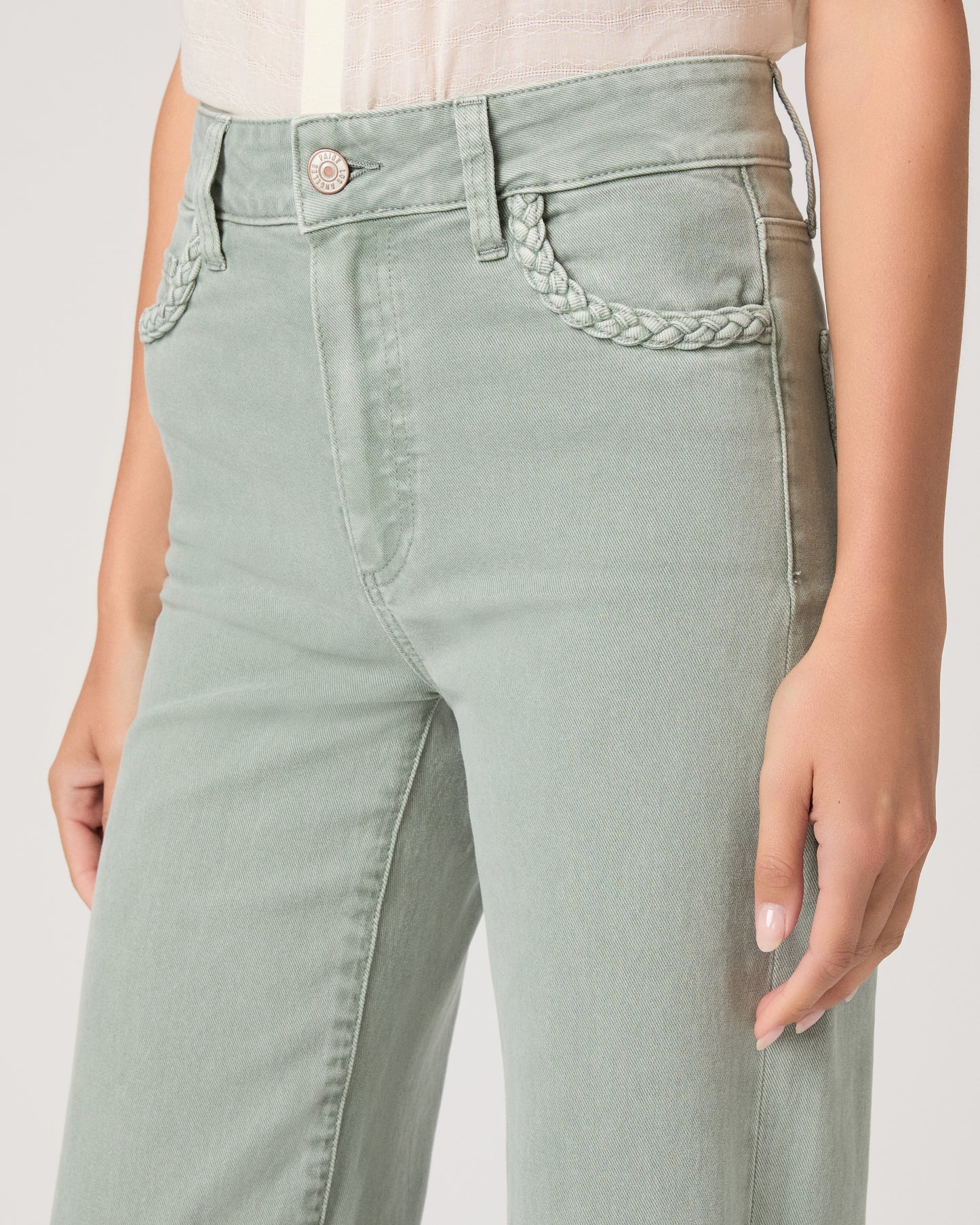 Model wearing a light green pant paired with a white top and brown sandals