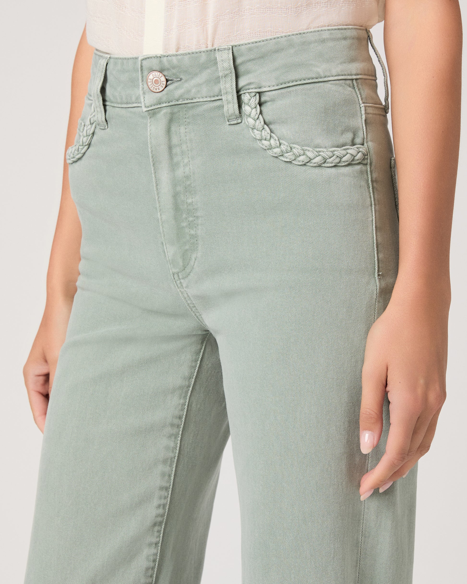 Model wearing a light green pant paired with a white top and brown sandals