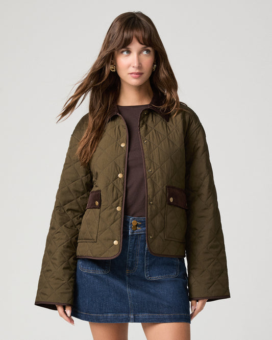 Woman wearing a brown top paired with a green jacket and denim skirt against a white background