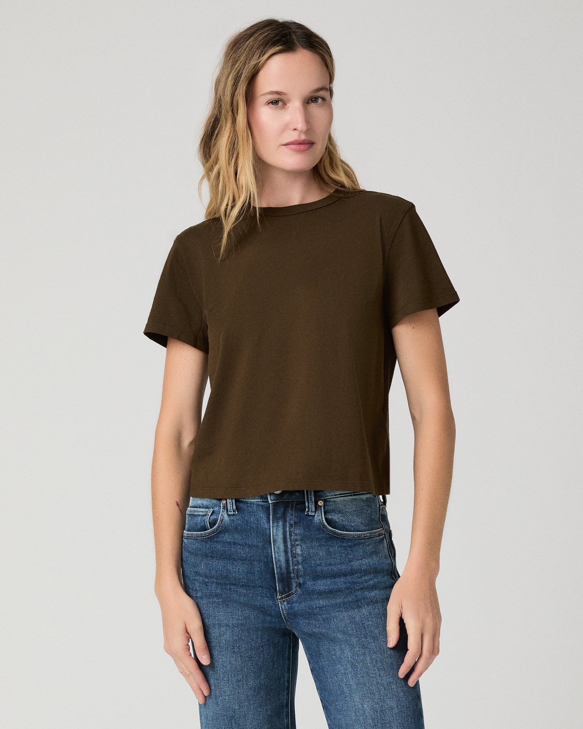 Women wearing green tee and blue jeans against a white background