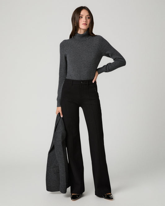 Women wearing a grey long sleeve top paired with black jeans and a grey blazer against a white background