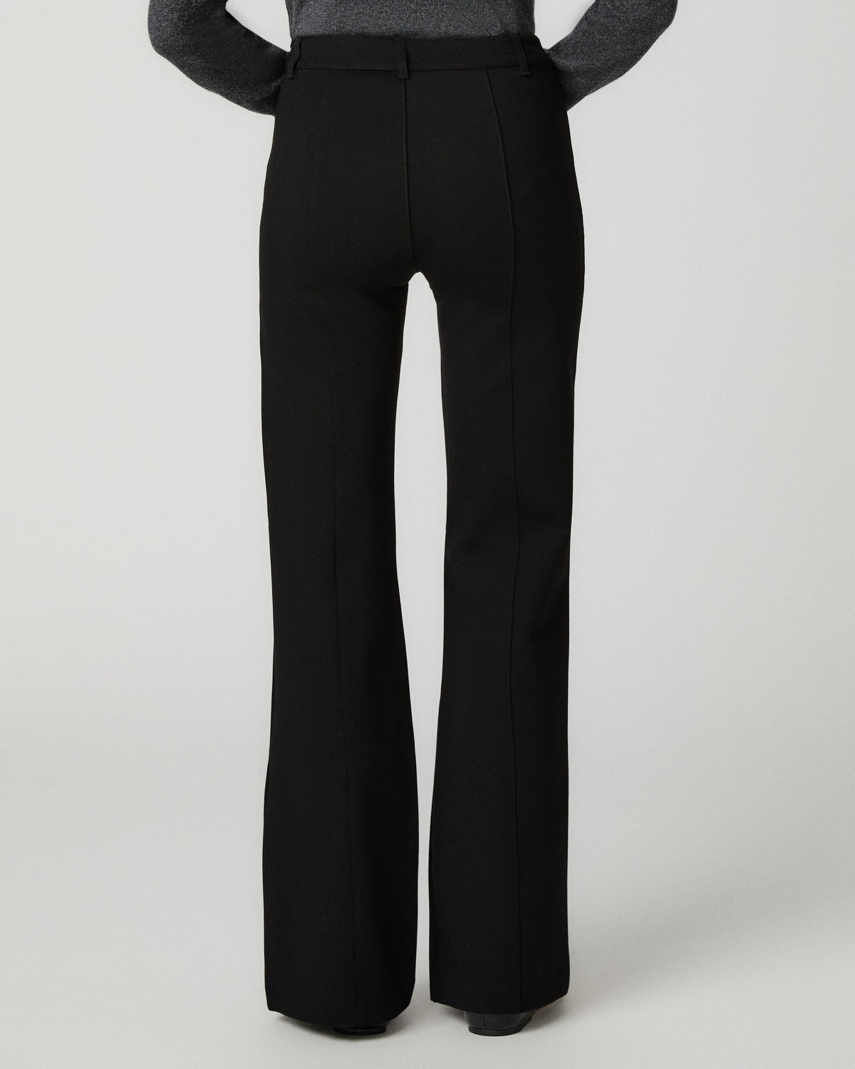 Women wearing a grey long sleeve top paired with black jeans against a white background