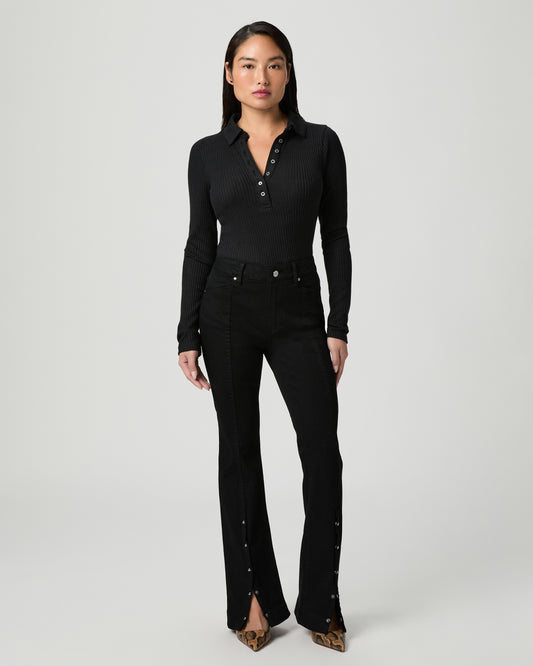 Woman wearing a black top and back jeans on a white background