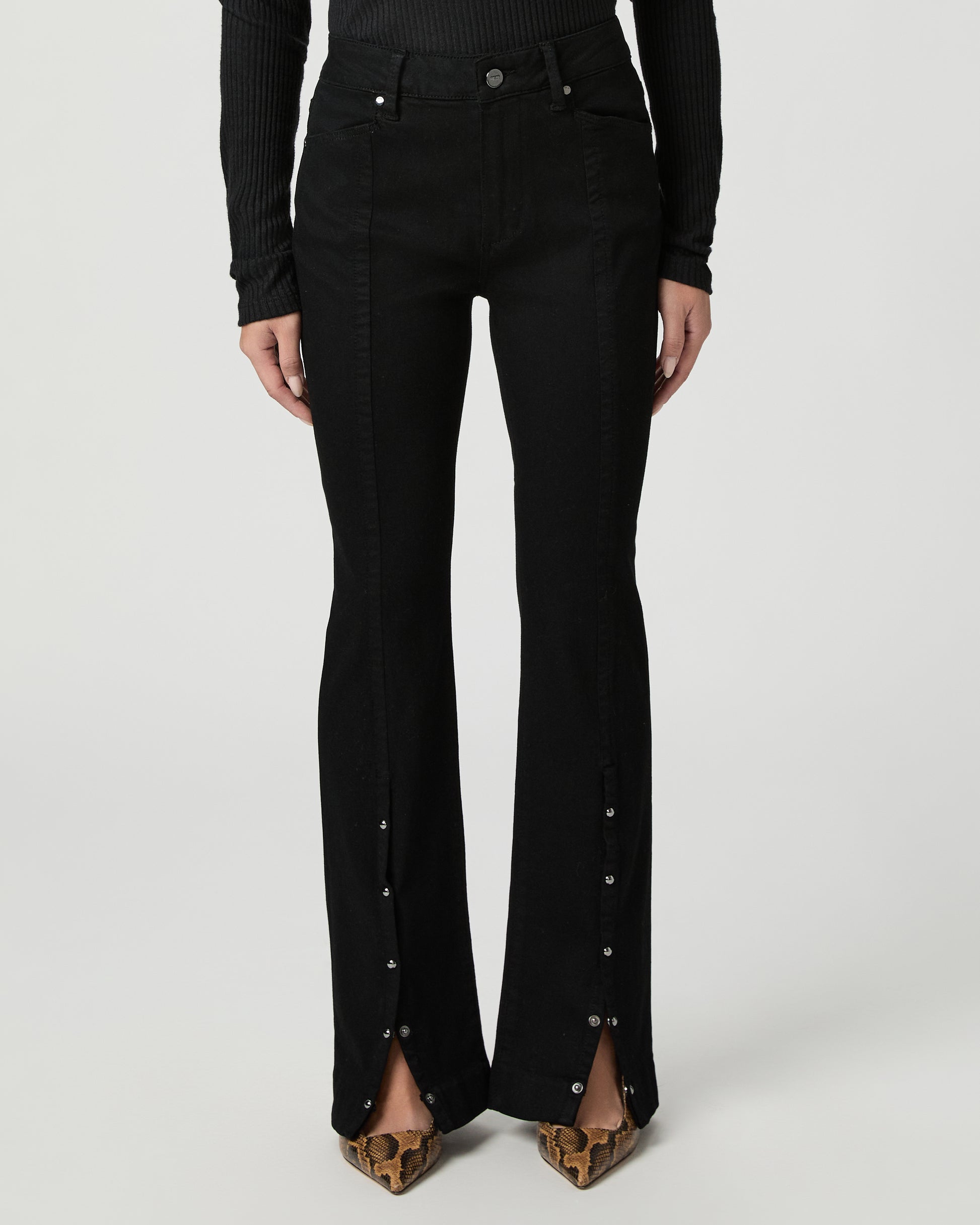 Woman wearing a black top and back jeans on a white background