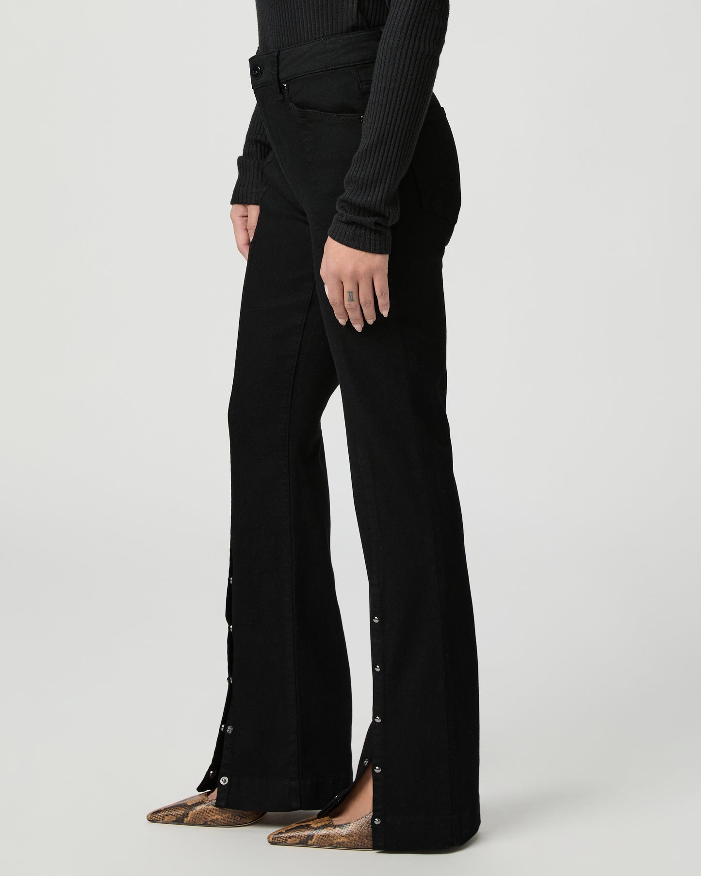 Woman wearing a black top and back jeans on a white background
