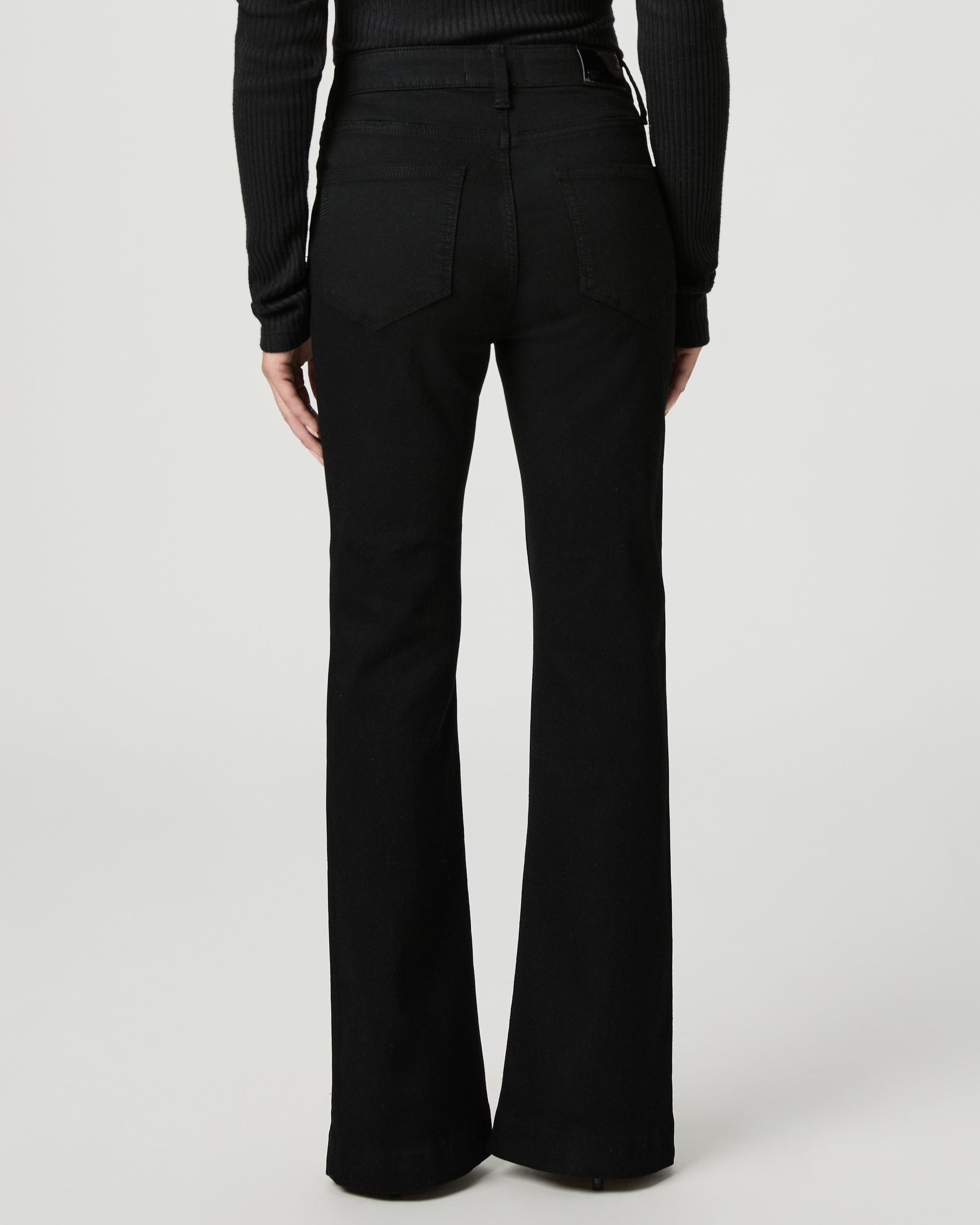 Woman wearing a black top and back jeans on a white background