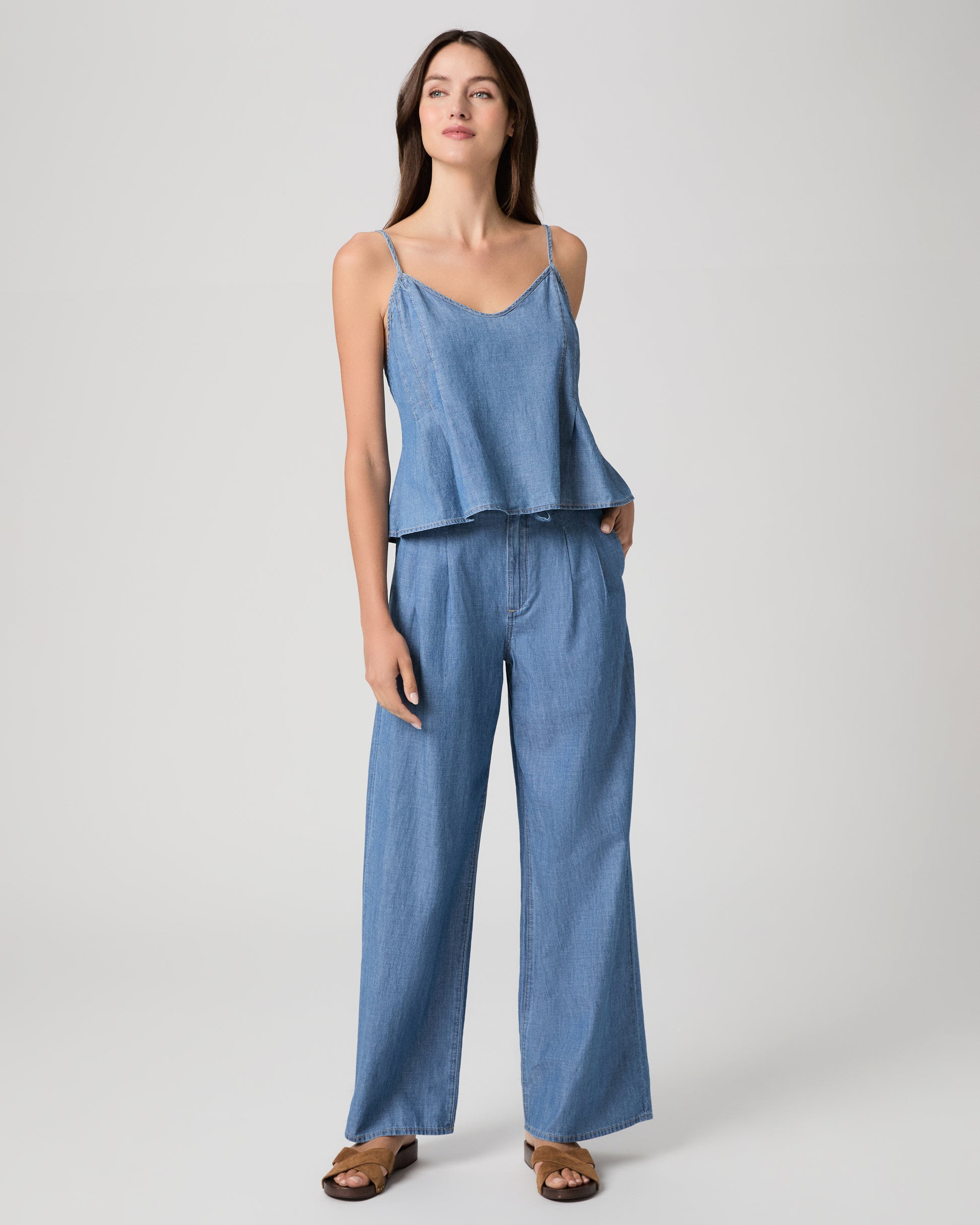 Woman wearing a blue denim top and pants on a light gray background