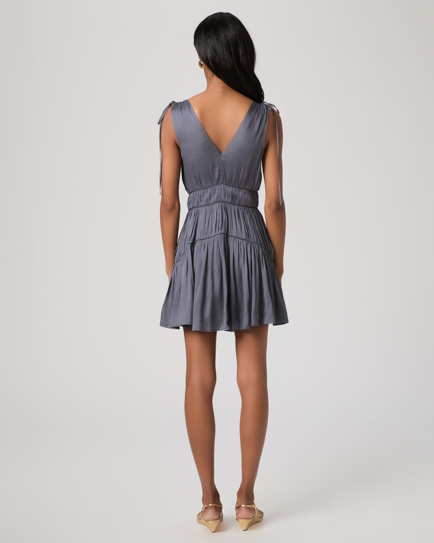 Women wearing a gray mini dress paired with gold sandals against a white background