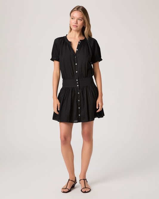 Model wearing a black dress paired with dark brown sandals against a white background. 