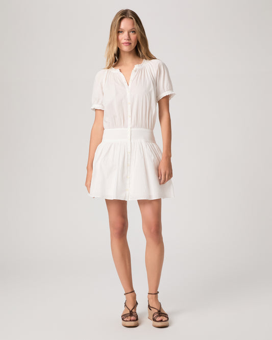 Model wearing a white dress paired with brown wedges against a white background. 