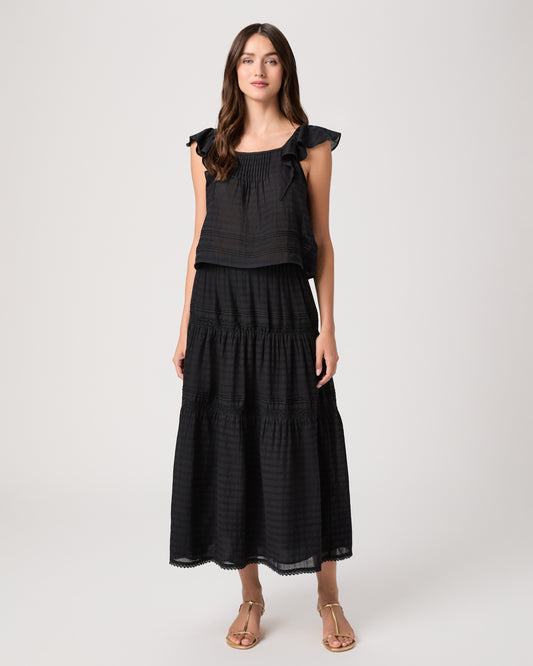 Model wearing a black midi skirt paired with a black  top and gold sandals