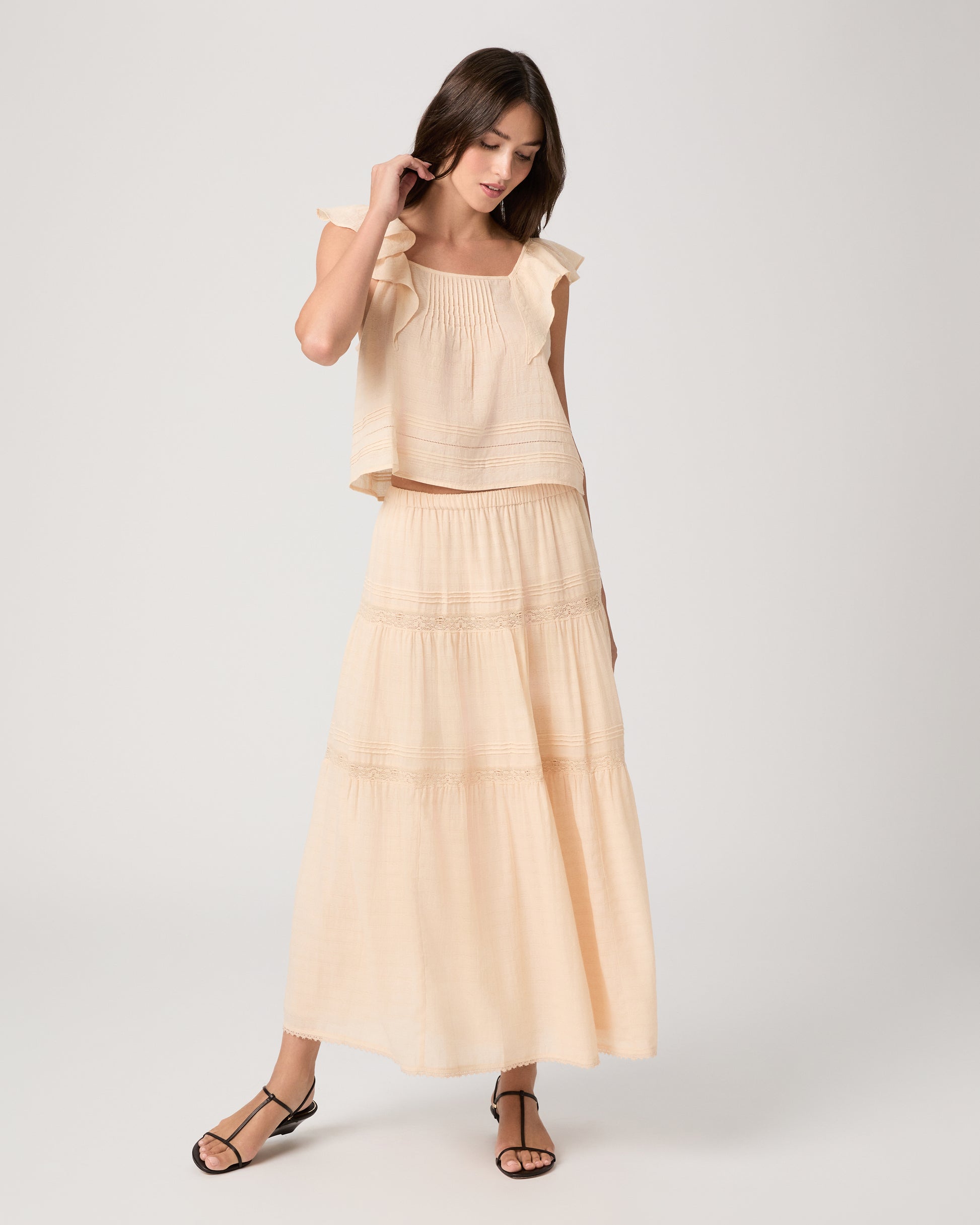 Model wearing a light peach midi skirt paired with a light peach top and brown sandals