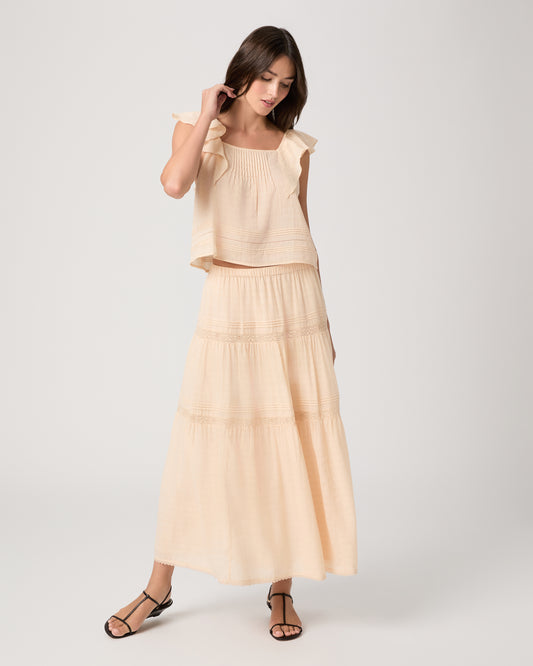 Model wearing a light peach midi skirt paired with a light peach top and brown sandals