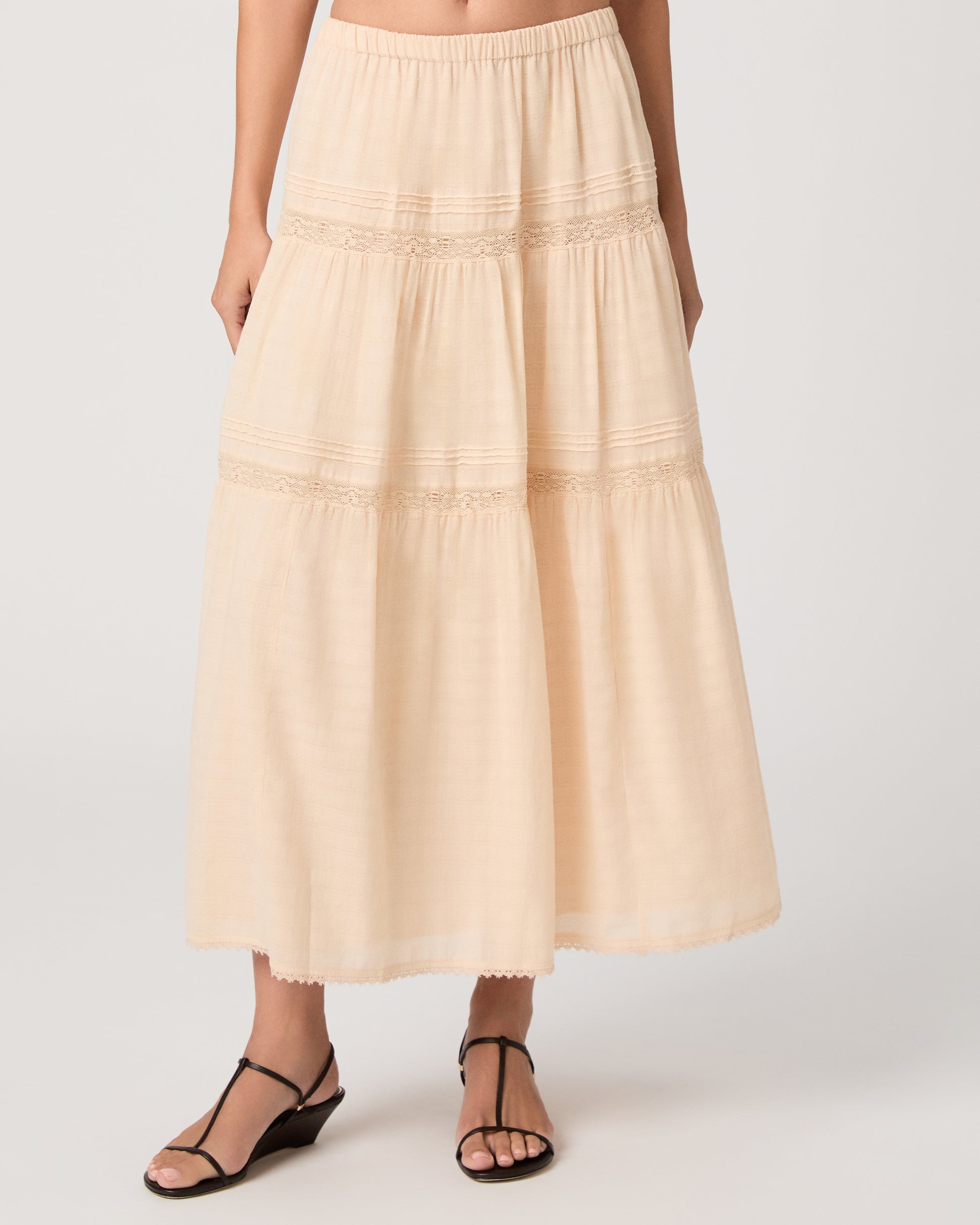 Model wearing a light peach midi skirt paired with a light peach top and brown sandals