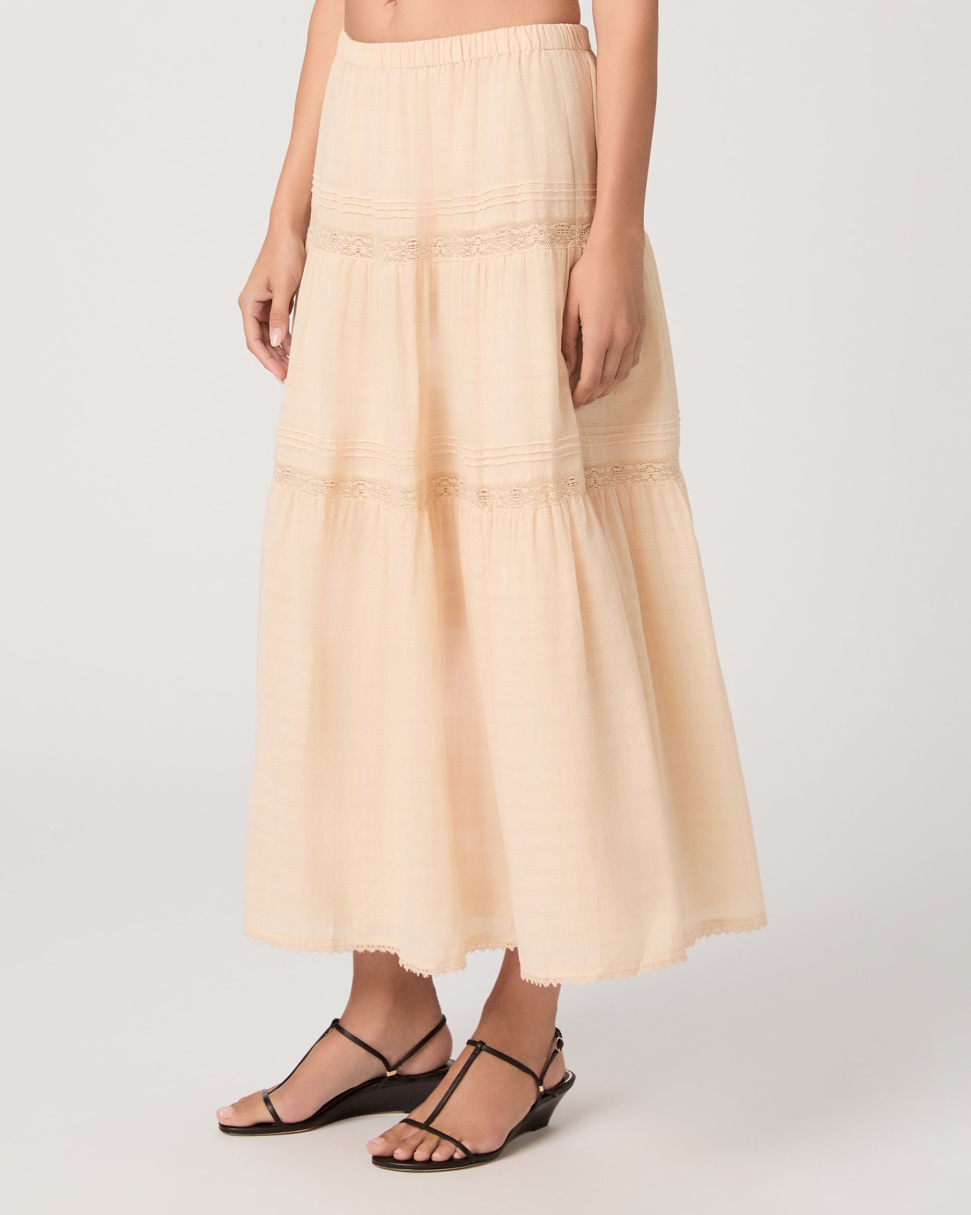 Model wearing a light peach midi skirt paired with a light peach top and brown sandals