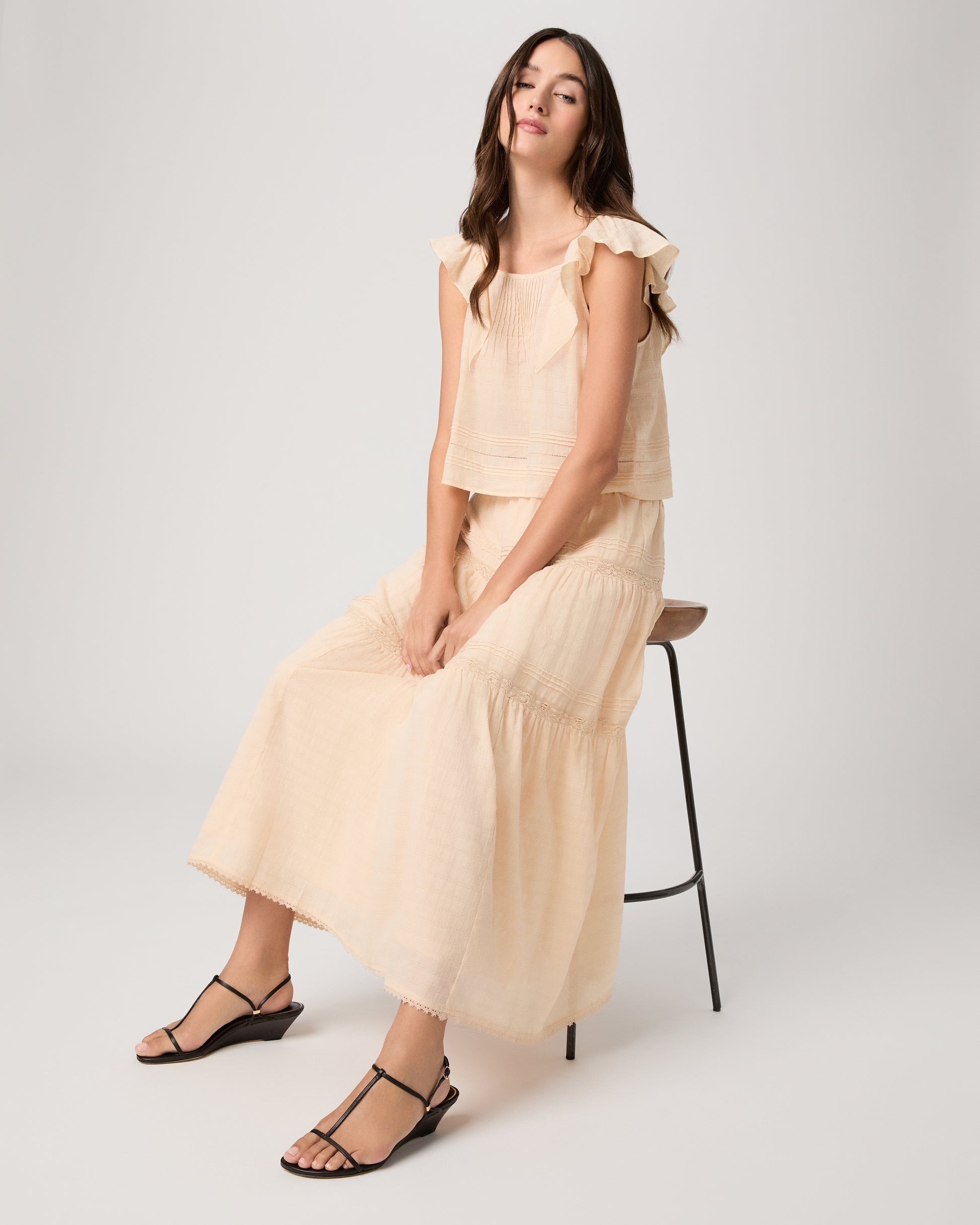 Model wearing a light peach midi skirt paired with a light peach top and brown sandals