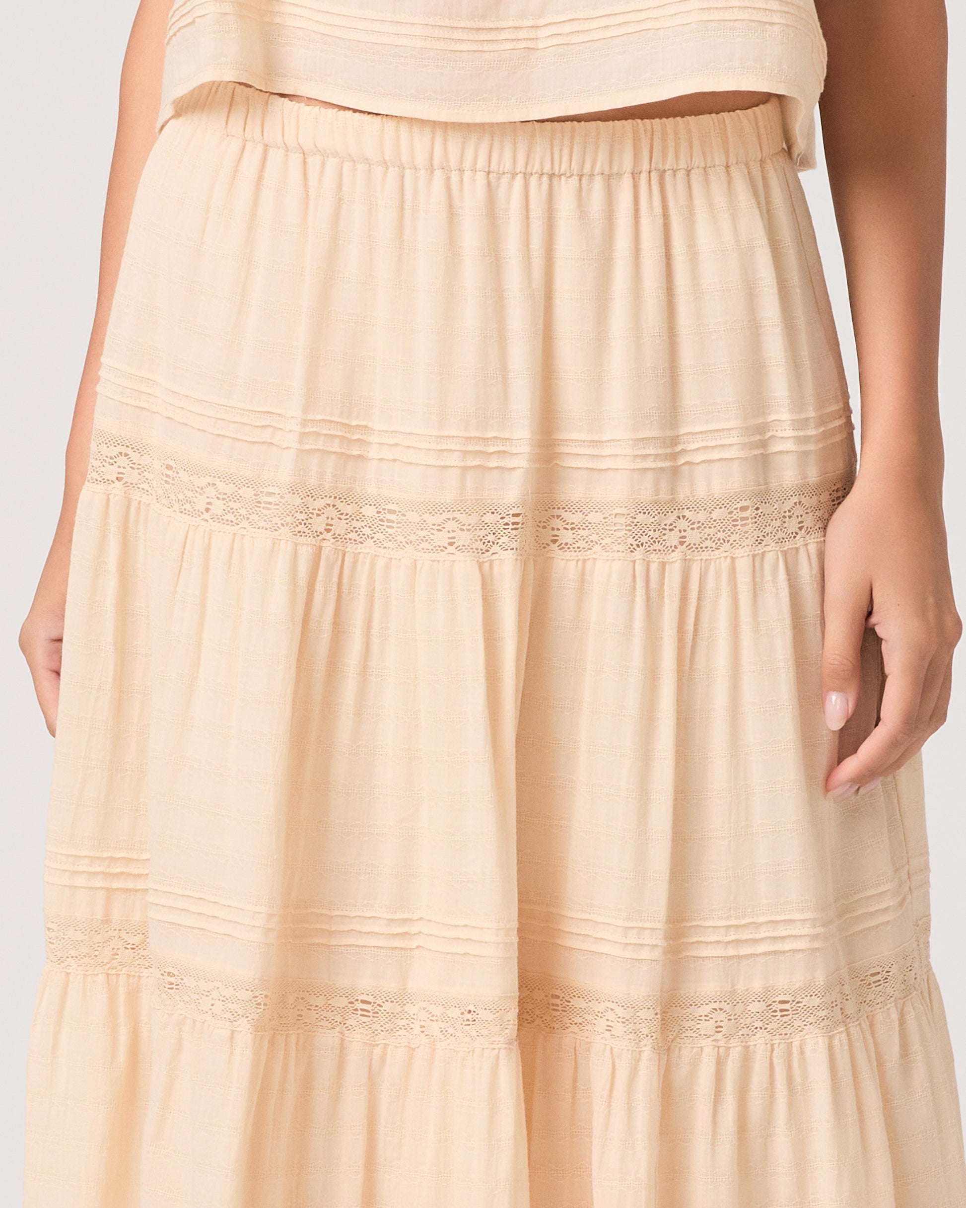 Model wearing a light peach midi skirt paired with a light peach top and brown sandals